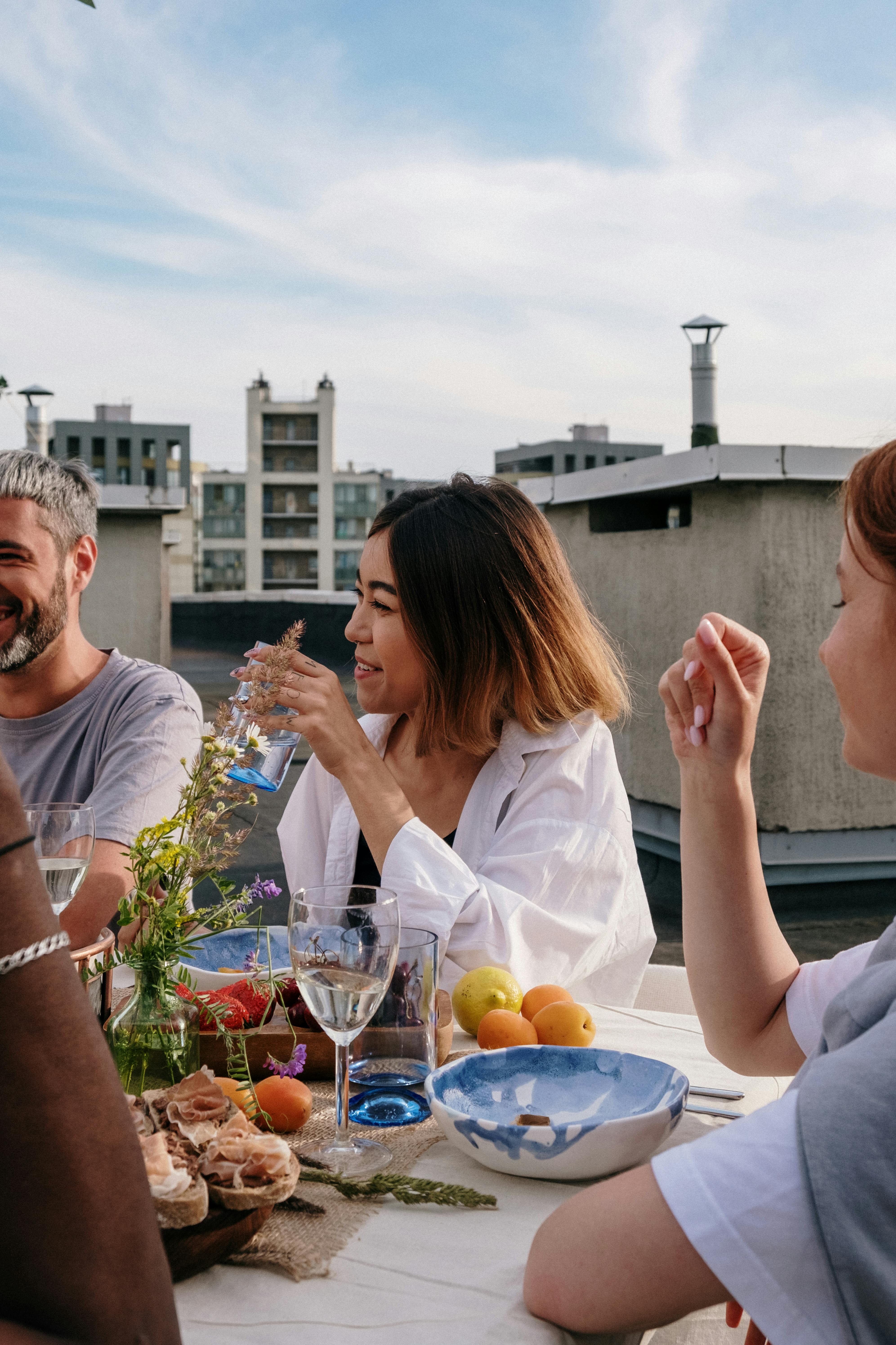 Menschen reden und lachen an einem Tisch voller Essen | Quelle: Pexels