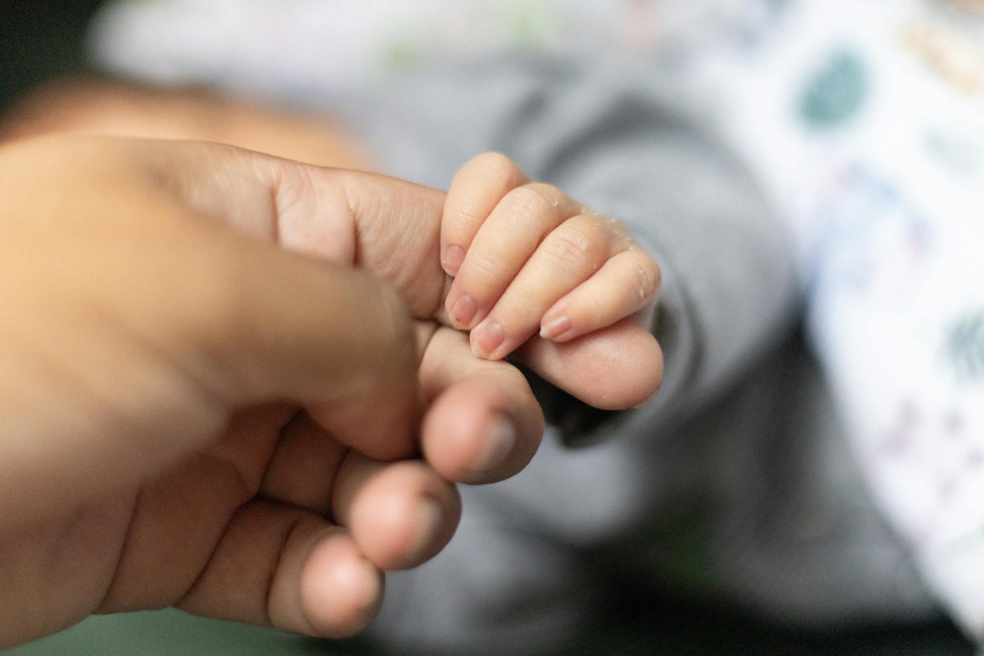 Ein Baby, das den Finger eines Mannes hält | Quelle: Pexels