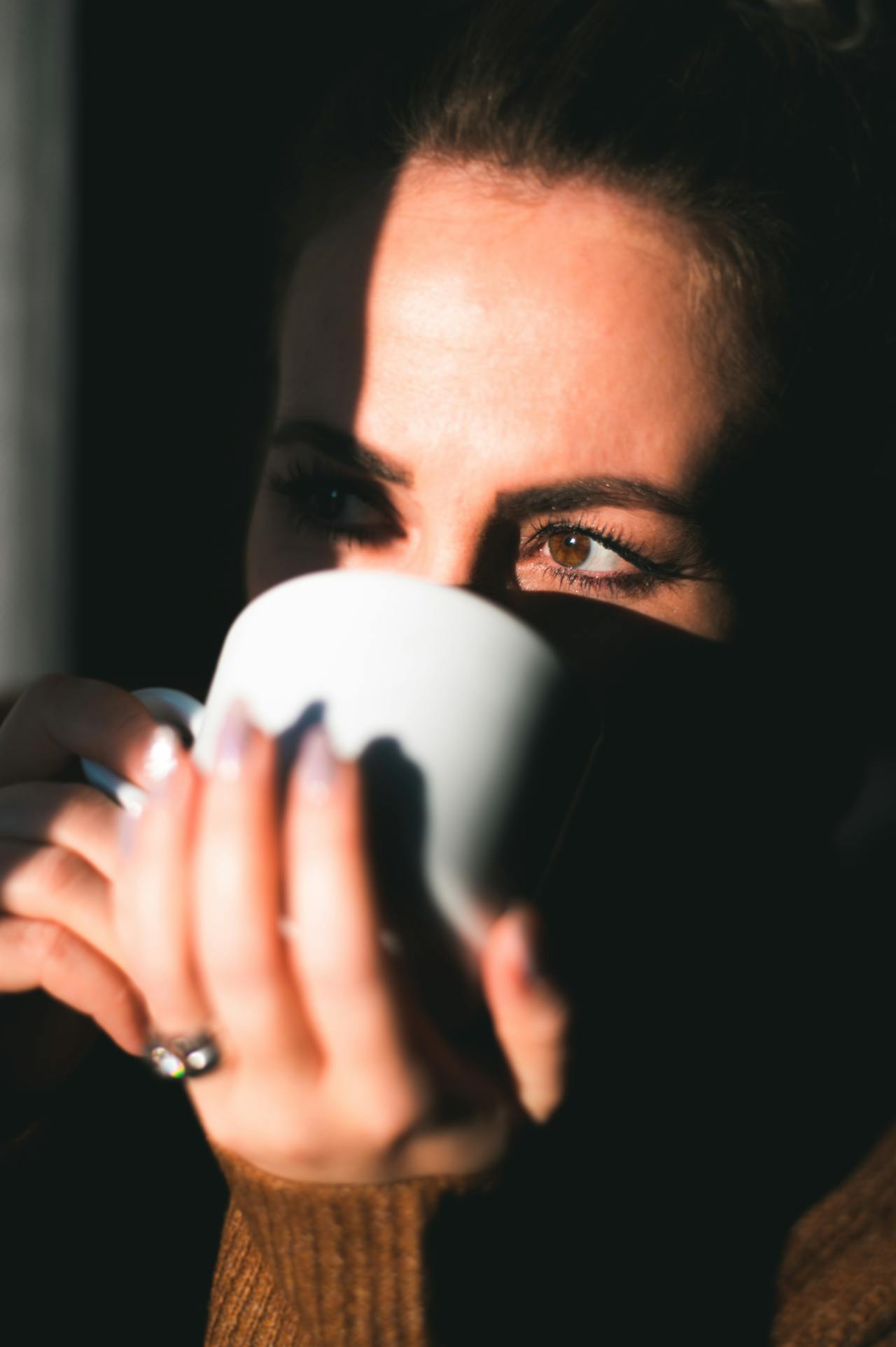 Eine Frau trinkt ein Getränk aus einer weißen Keramiktasse | Quelle: Pexels