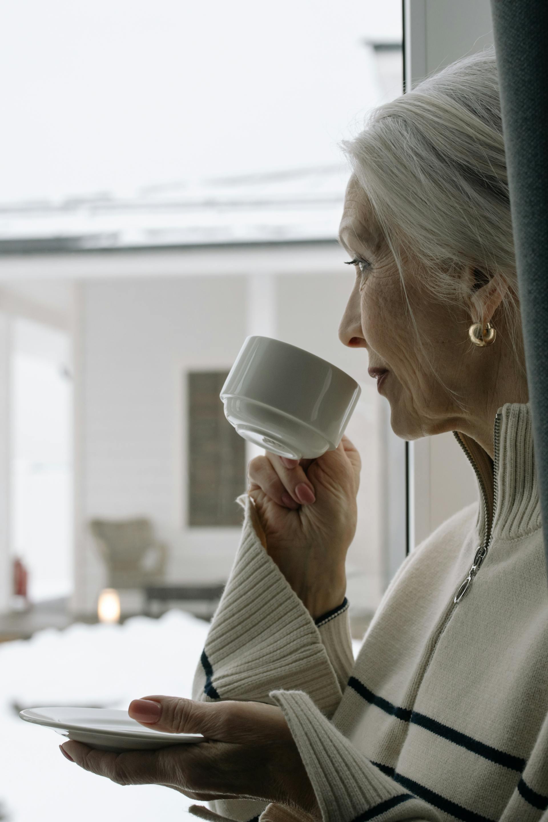 Eine Frau lächelt schwach, während sie aus dem Fenster schaut | Quelle: Pexels