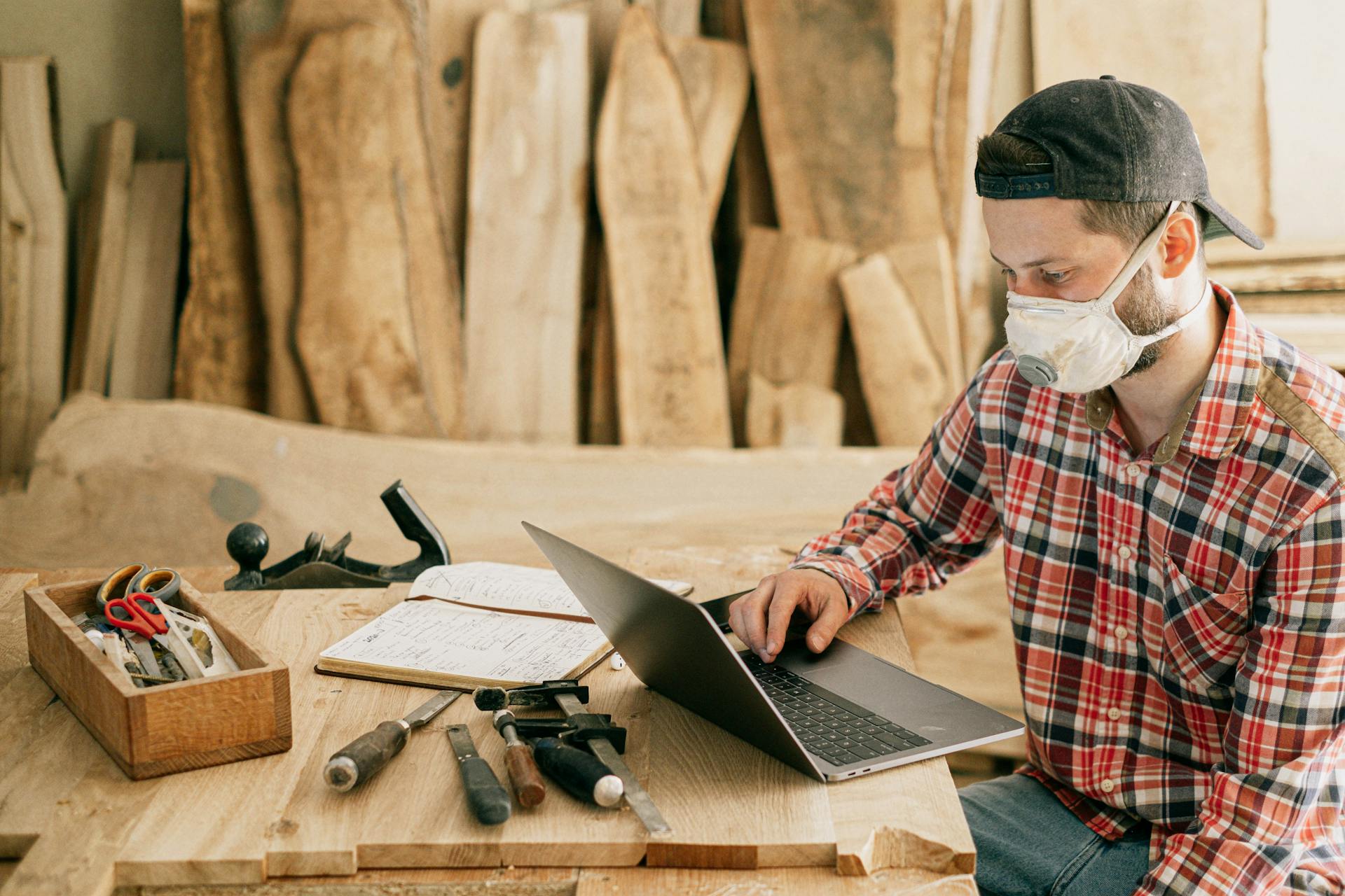 Ein Mann benutzt einen Laptop in einer Holzwerkstatt | Quelle: Pexels