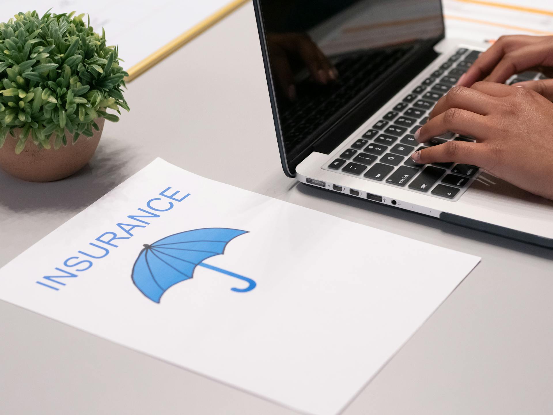 Ein Blatt Papier neben einer Person, die auf einem Laptop tippt | Quelle: Pexels