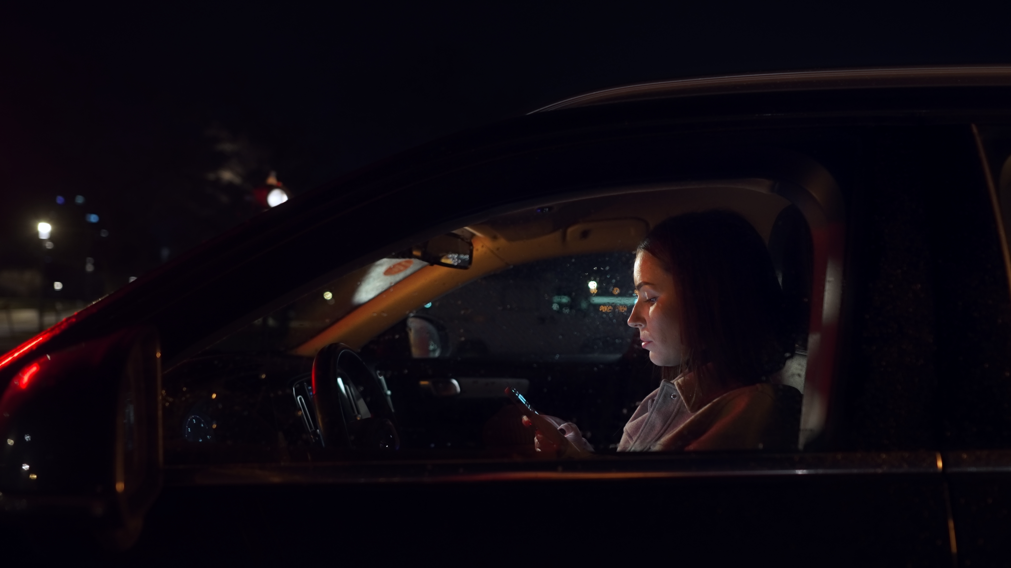 Frau benutzt ihr Smartphone nachts in einem Auto | Quelle: Shutterstock
