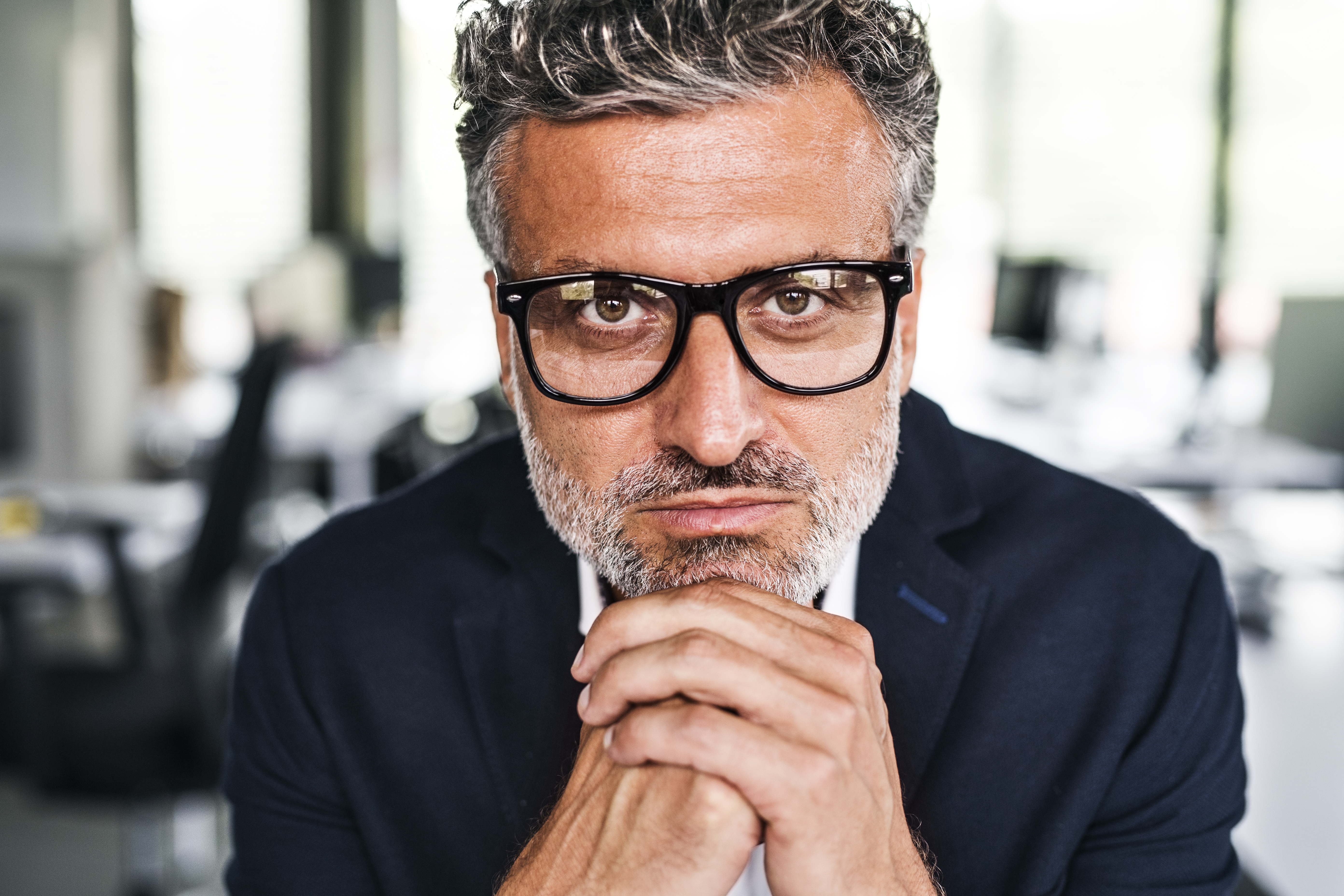 Porträt eines ernsten, reifen Geschäftsmannes mit Brille im Büro | Quelle: Getty Images