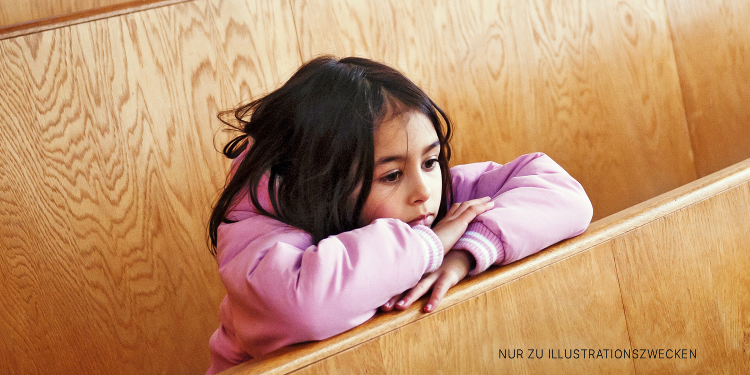 Kleines Mädchen lehnt zwischen den Kirchenbänken. | Quelle: Getty Images