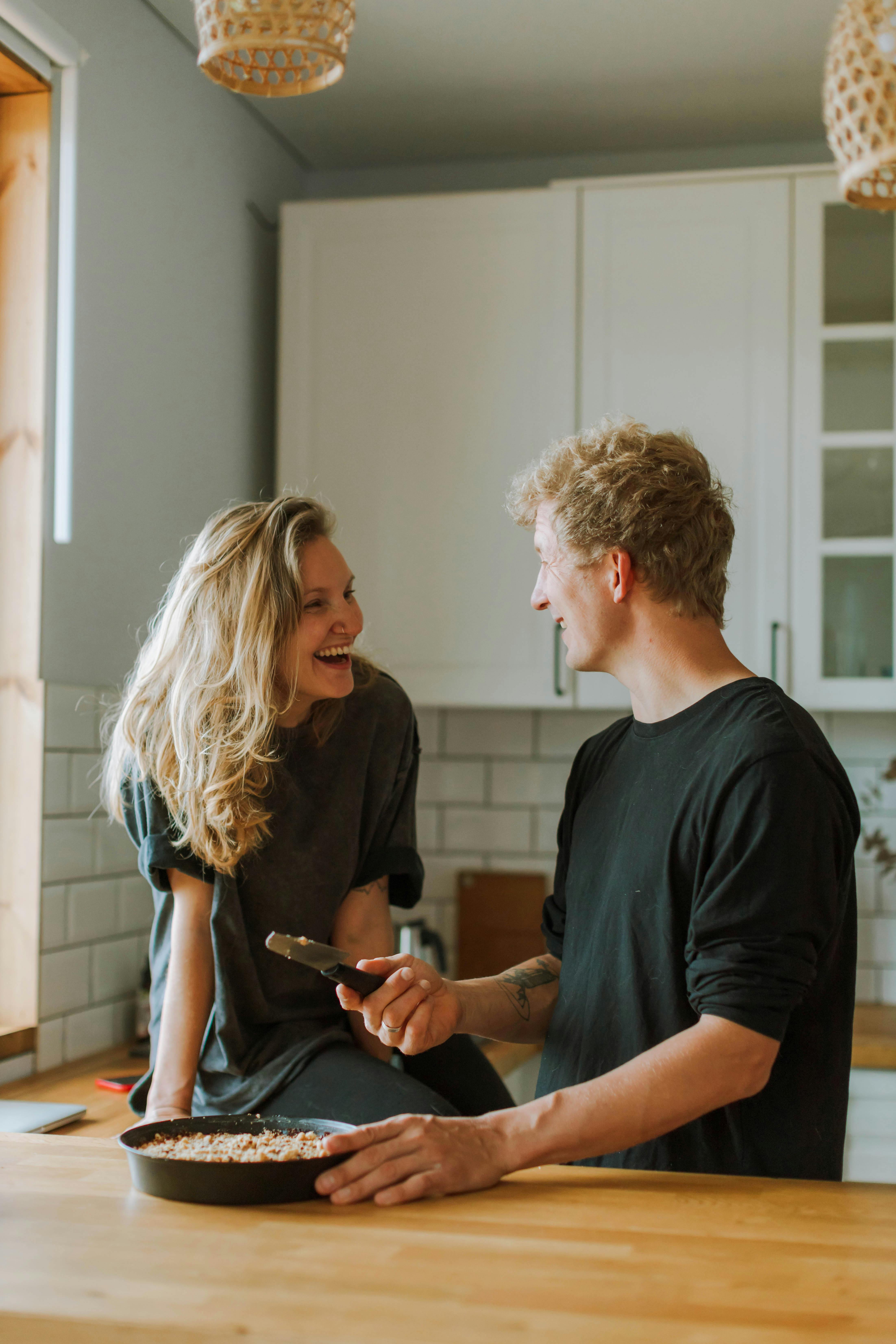 Mann und Frau lachen bei der Zubereitung einer Mahlzeit in der Küche | Quelle: Pexels