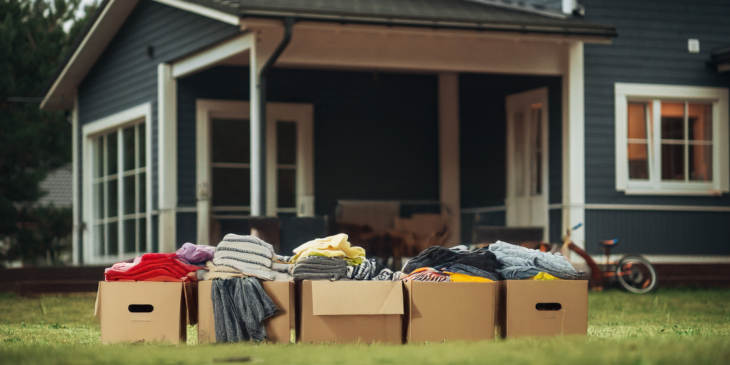 Ein Stapel Kleidung in Kisten, die vor einem Haus gestapelt sind | Quelle: Shutterstock