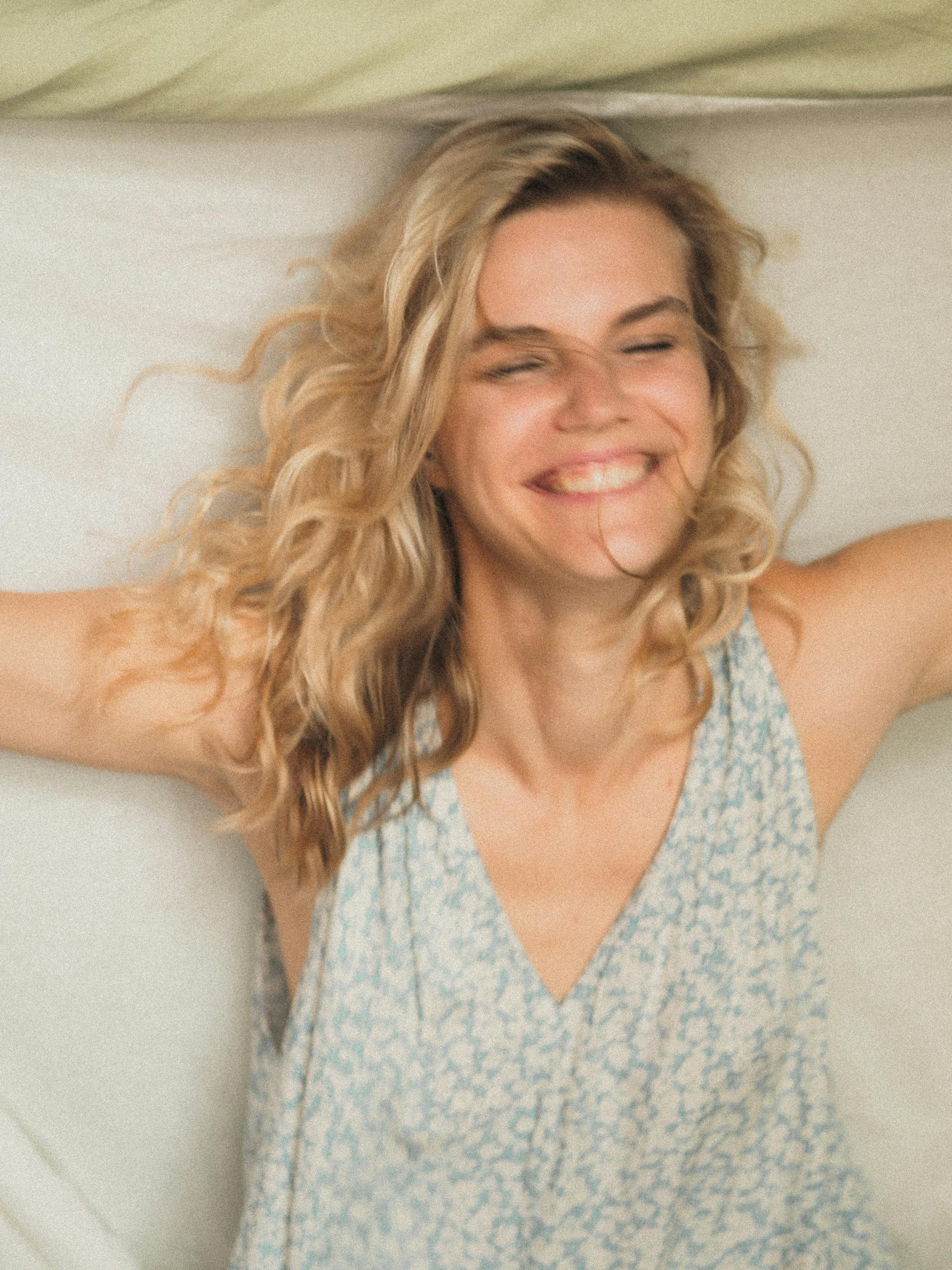 Eine Frau, die lachend auf einem Bett liegt | Quelle: Pexels