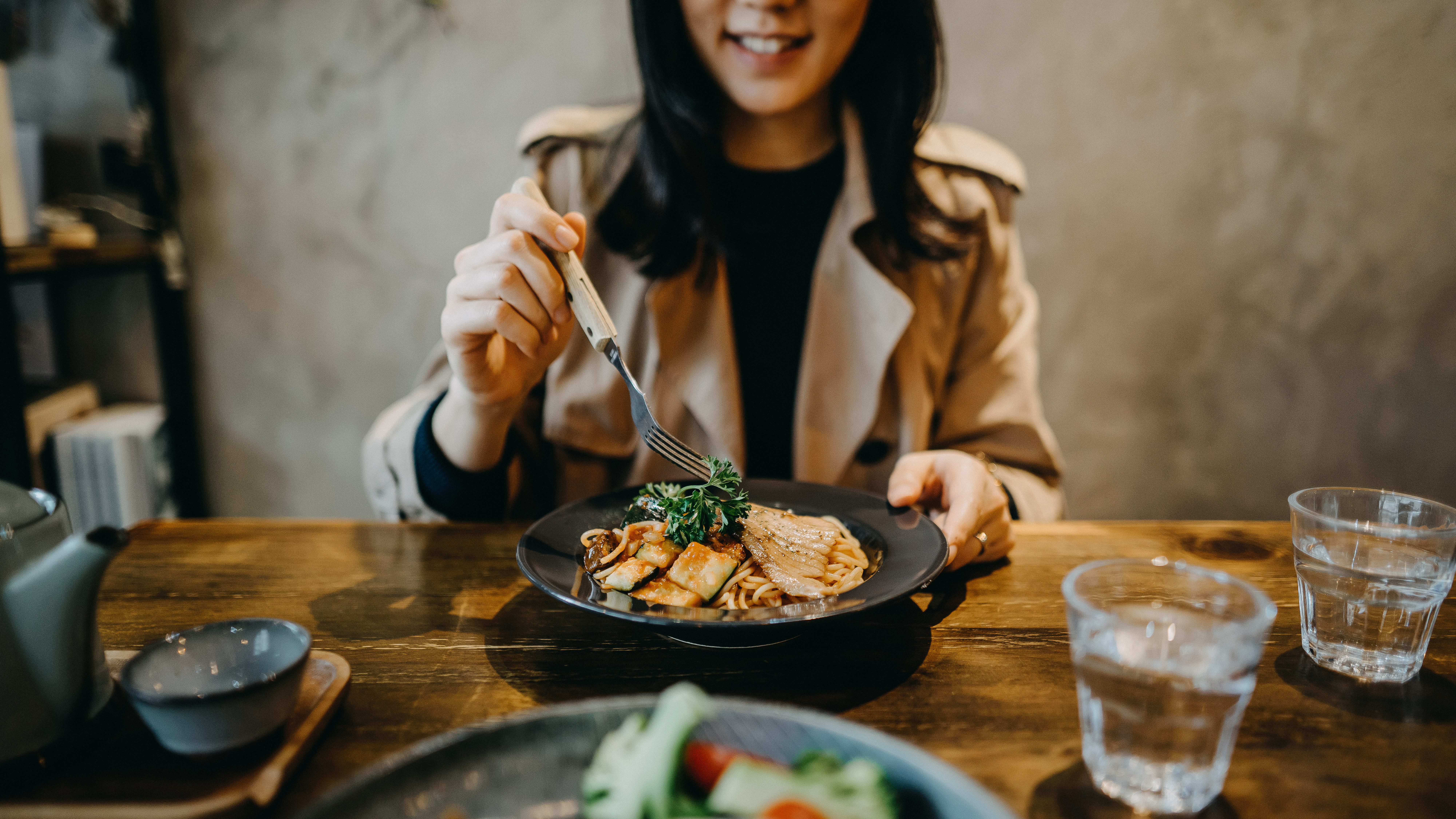 Eine lächelnde Frau beim Essen in einem Café | Quelle: Shutterstock