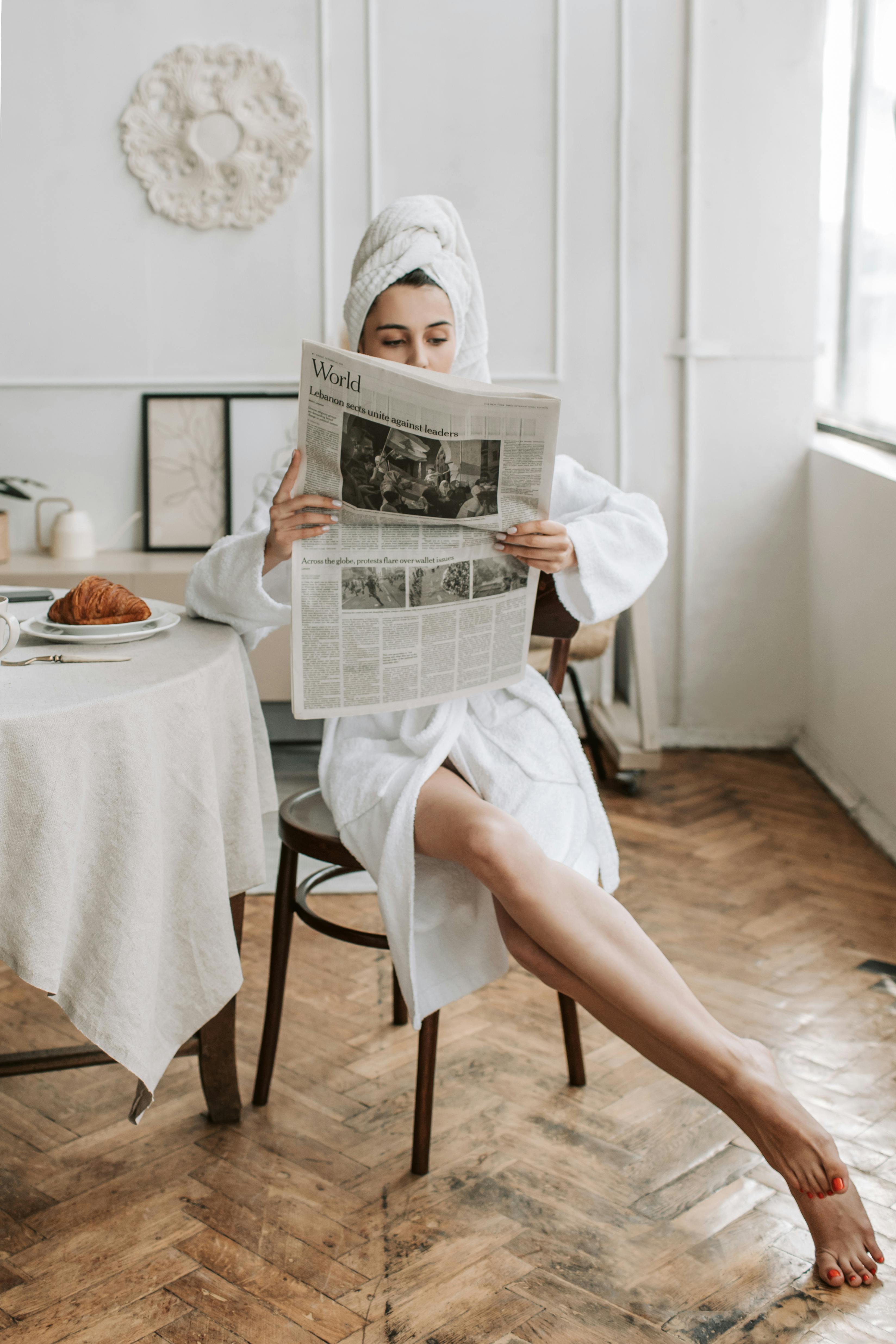 Eine Frau liest nach dem Duschen eine Zeitung | Quelle: Pexels