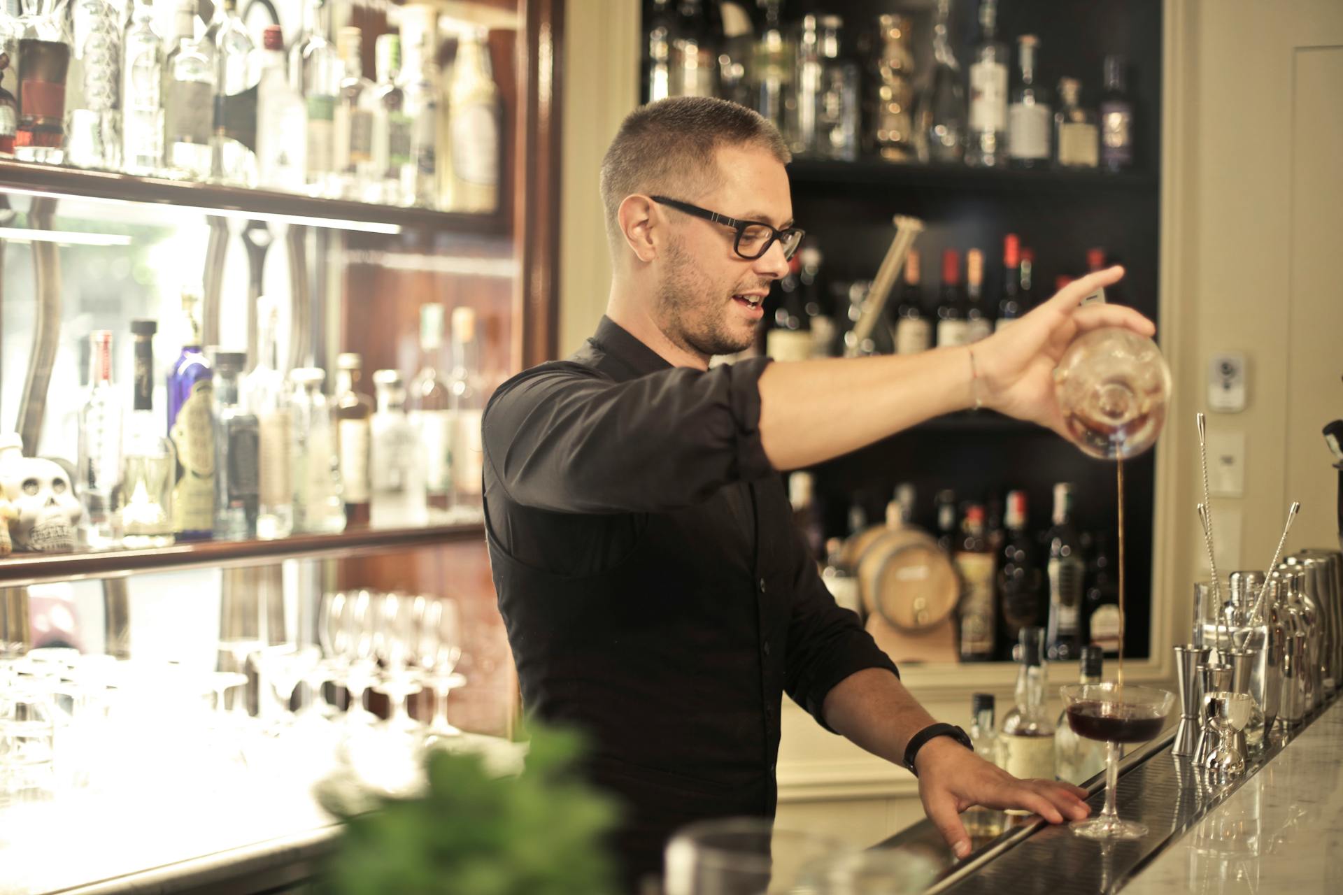 Ein Barkeeper schenkt Wein in ein Glas ein | Quelle: Pexels