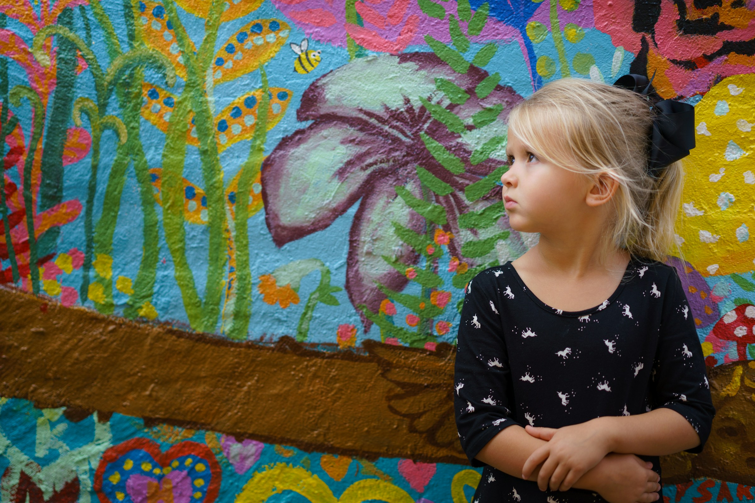 Ein kleines Mädchen, das vor einem blumigen Hintergrund steht | Quelle: Unsplash