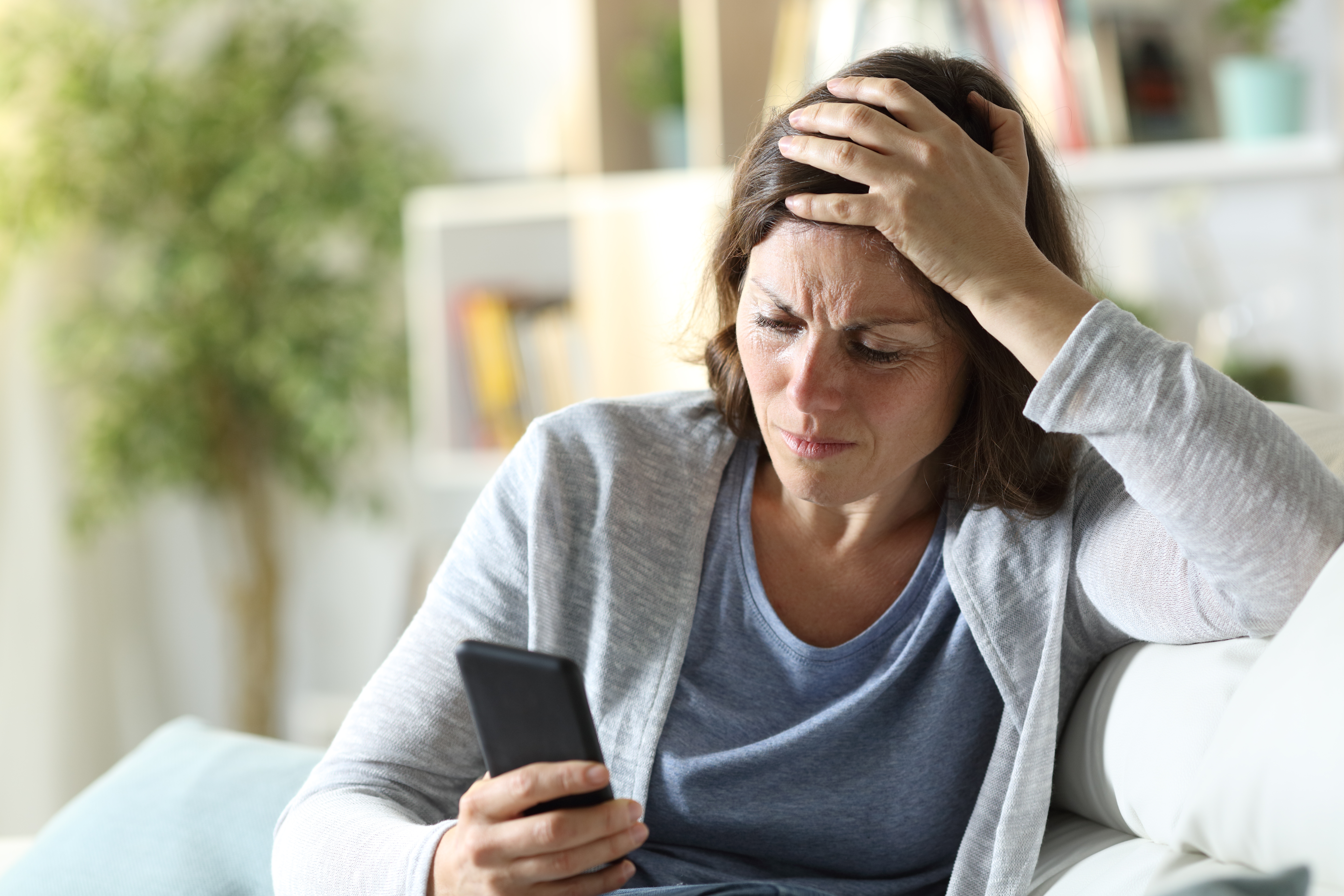 Eine Frau, die verwirrt und traurig auf ihr Telefon schaut | Quelle: Shutterstock