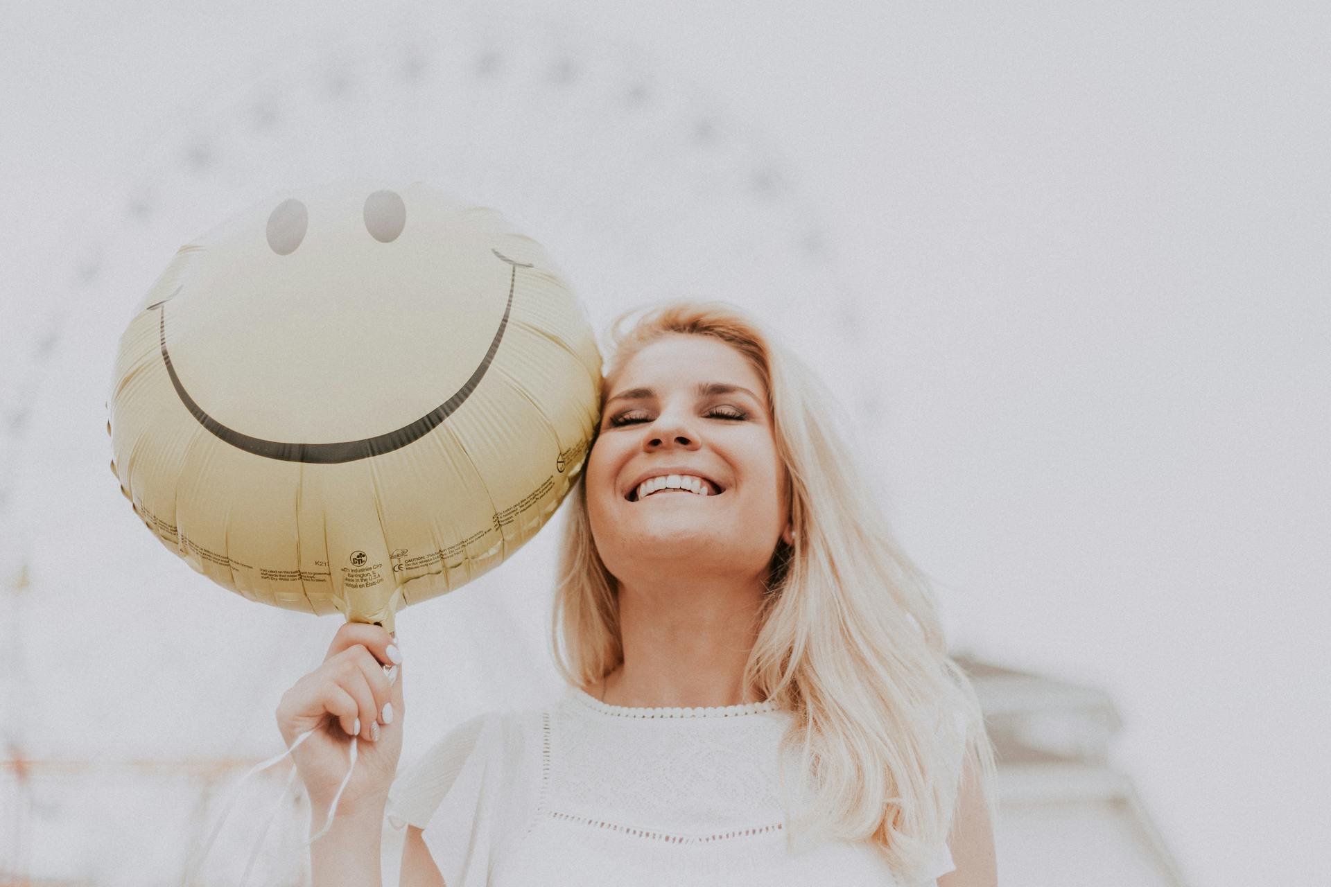 Frau hält lächelnd einen Luftballon | Quelle: Pexels