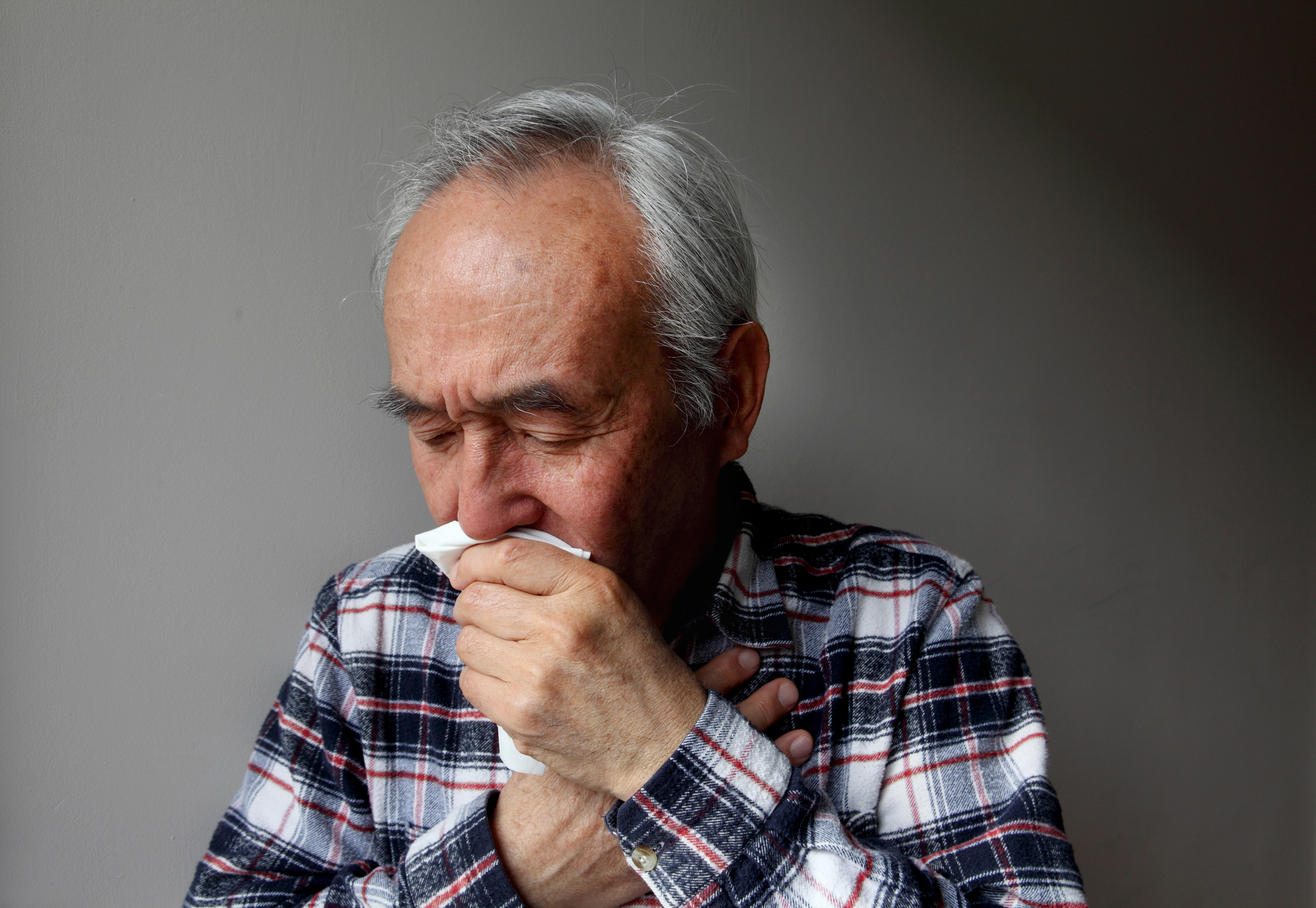 Alter Mann, der in eine Serviette hustet | Quelle: Getty Images