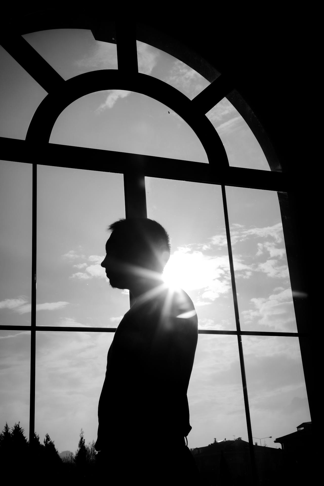 Ein Mann steht neben einem Bogenfenster | Quelle: Pexels