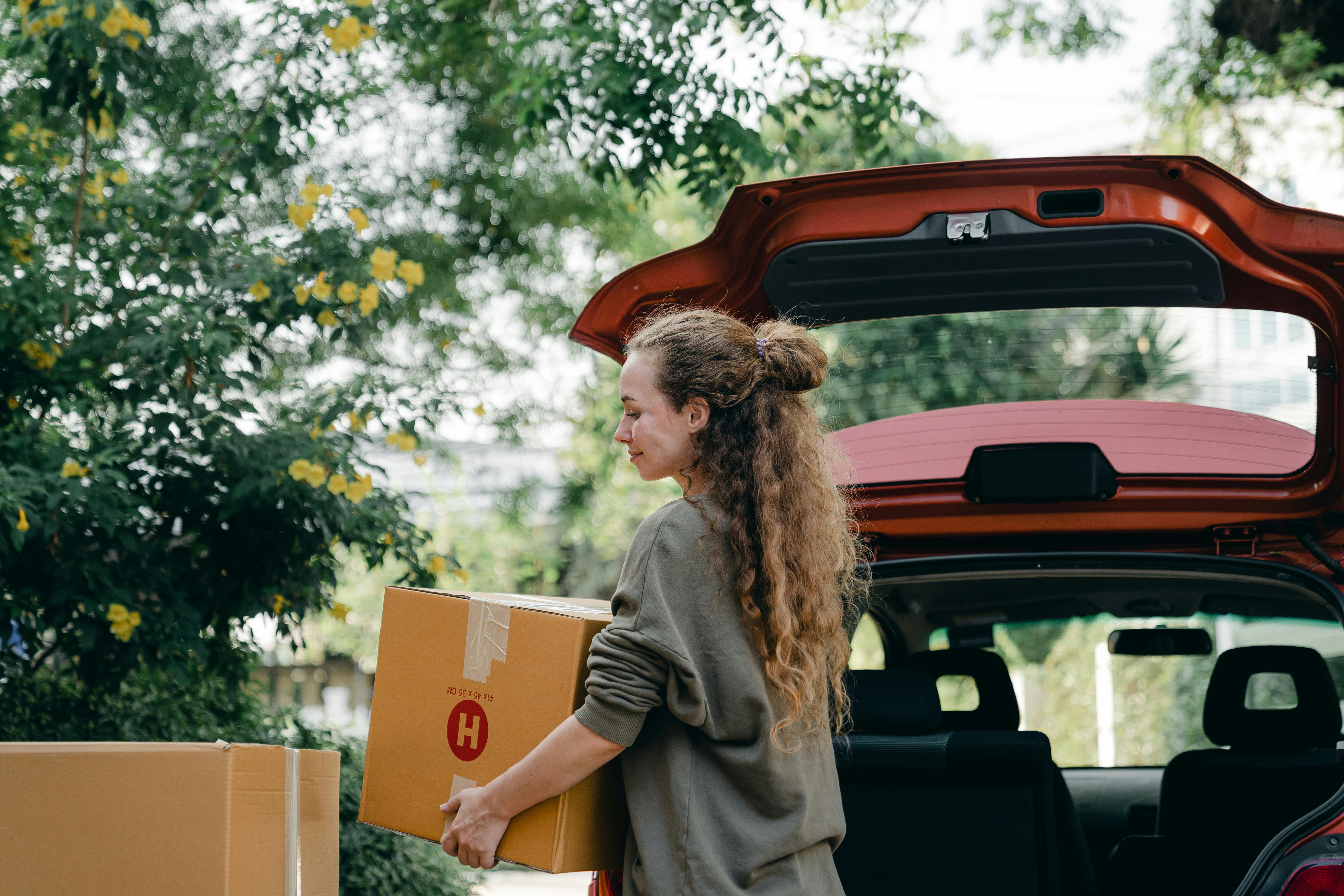 Eine glückliche Frau, die Kisten in ihr Auto lädt | Quelle: Pexels