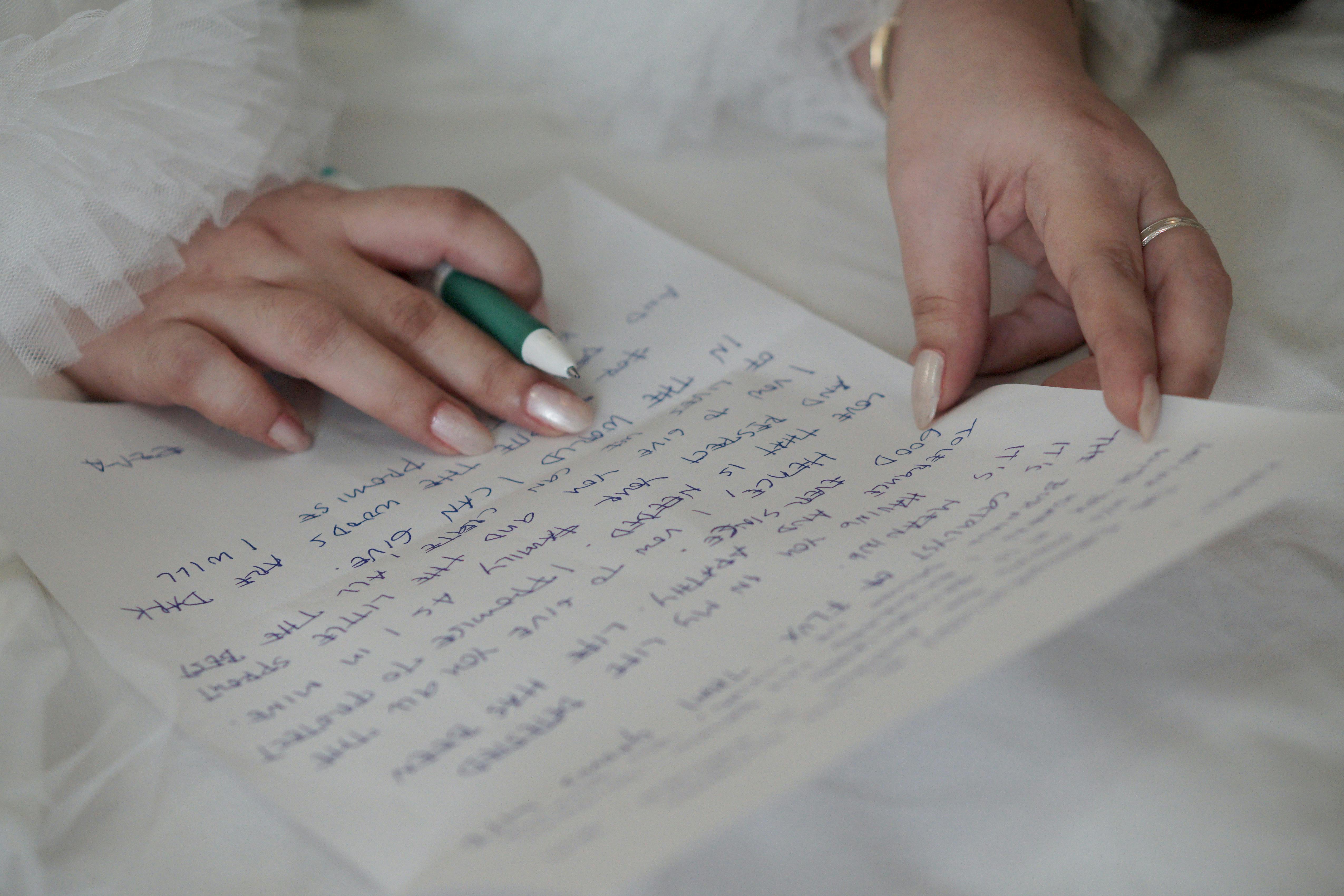 Die Hände einer Frau halten einen Stift, während sie einen Brief schreibt | Quelle: Pexels