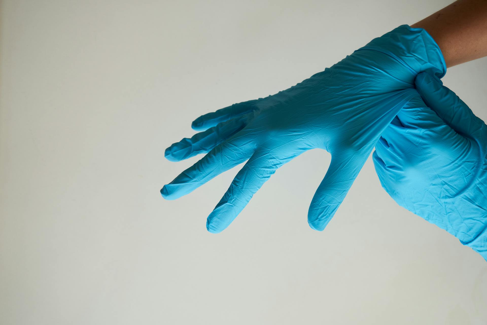 Eine Frau, die blaue Latexhandschuhe anzieht | Quelle: Pexels