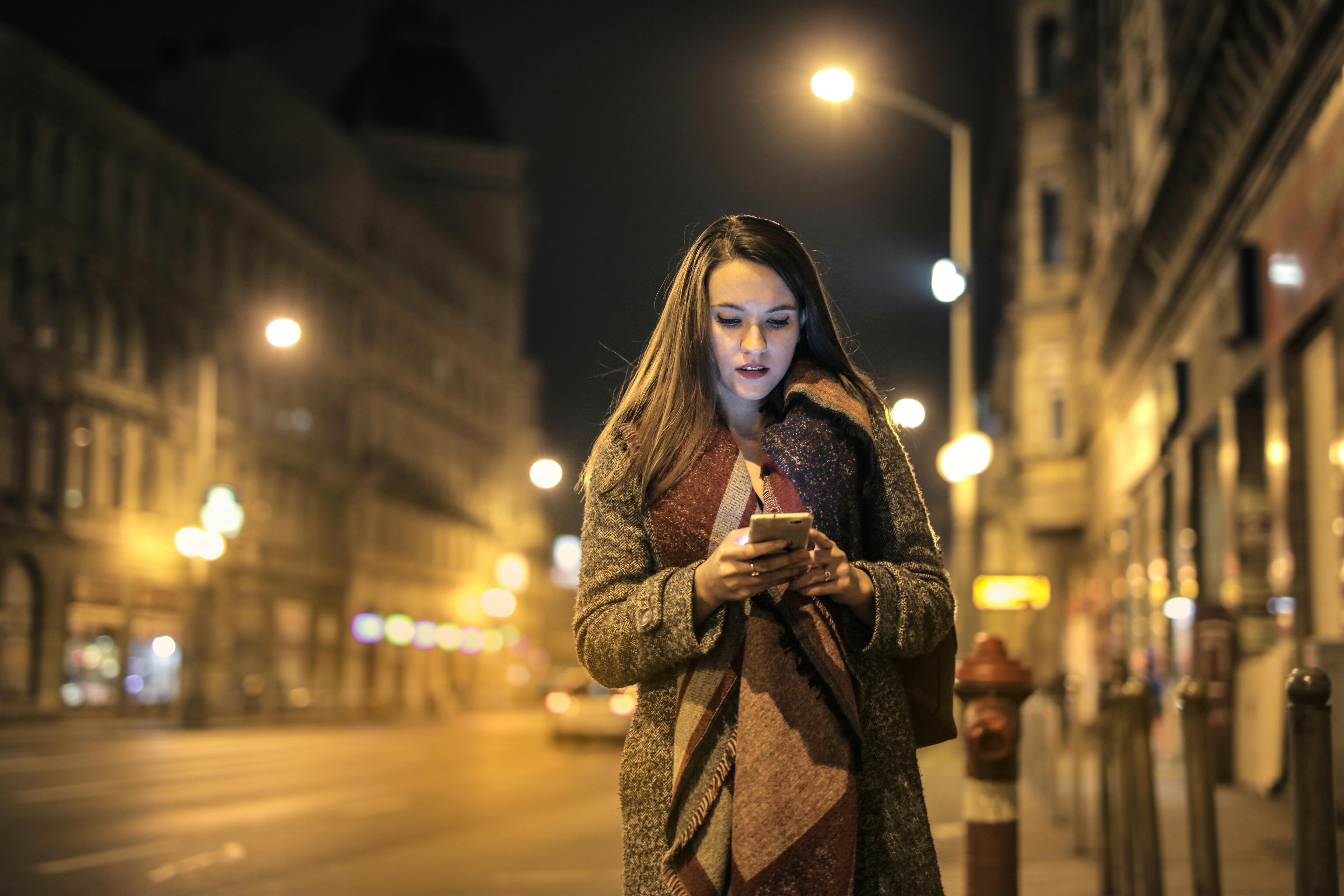 Eine Frau, die mitten auf der Straße auf ihr Handy schaut | Quelle: Pexels