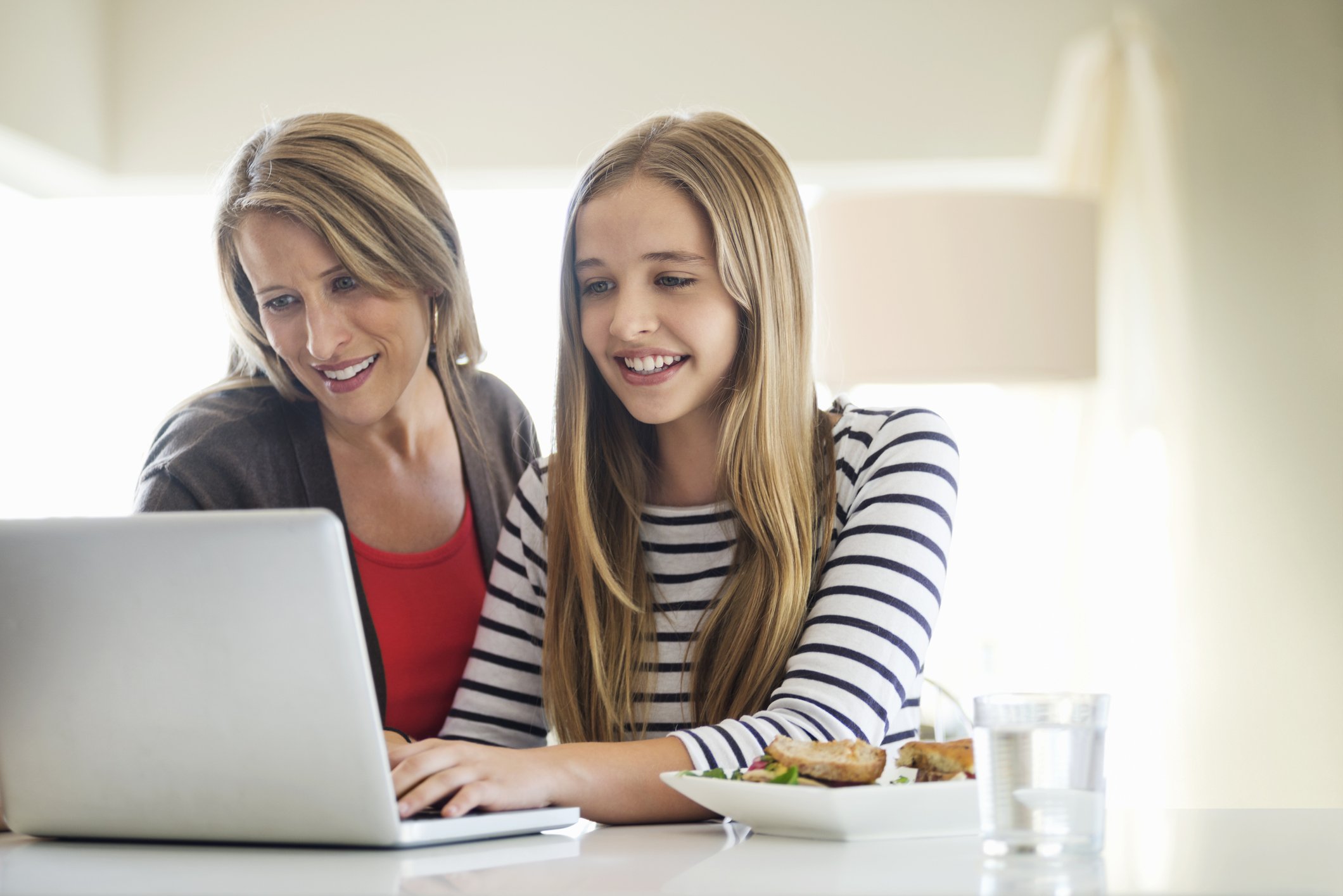 Mutter und Tochter benutzen Laptop zusammen zu Hause | Quelle: Getty Images