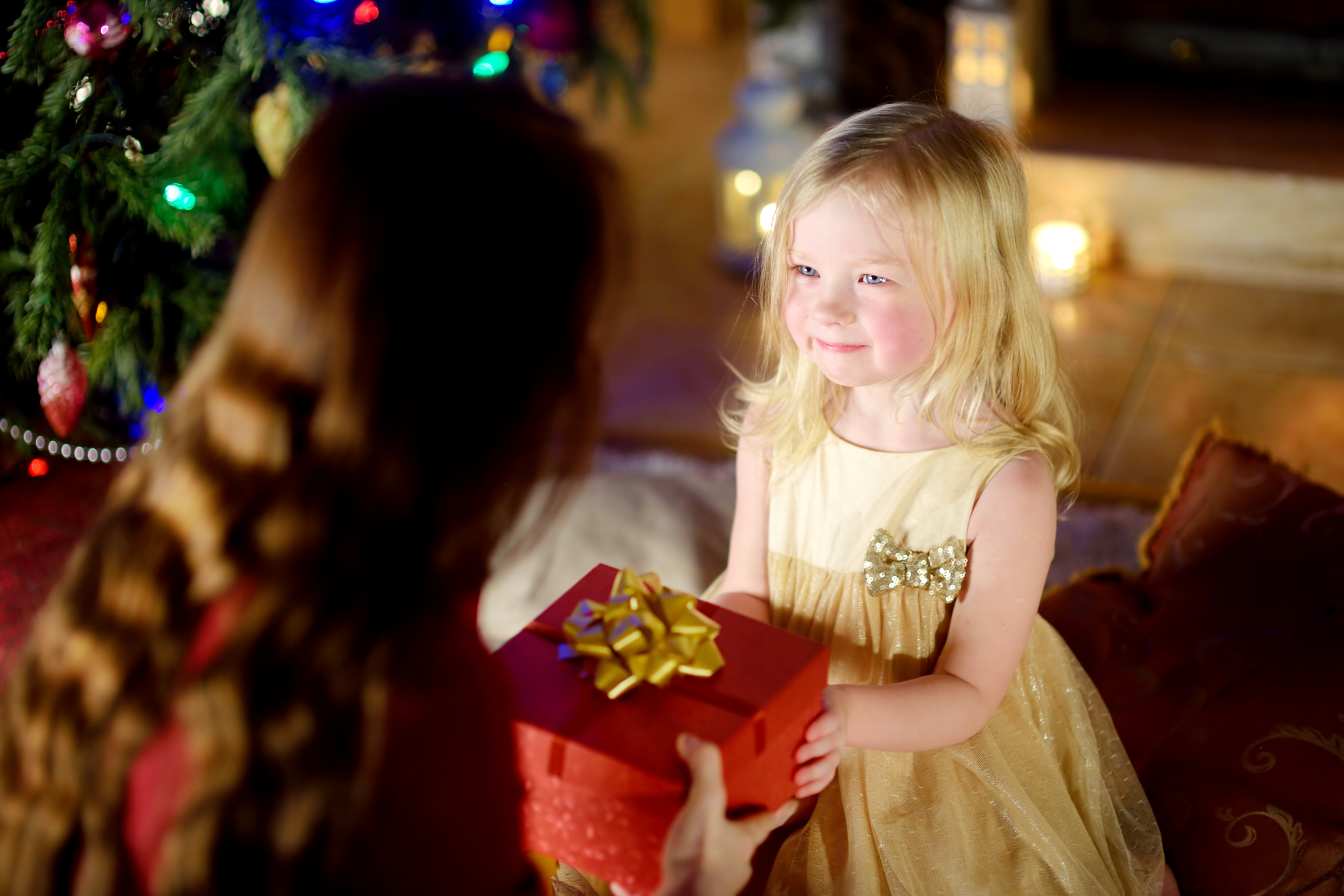 Ein glückliches kleines Mädchen, das ein Weihnachtsgeschenk von seiner Mutter bekommt | Quelle: Getty Images