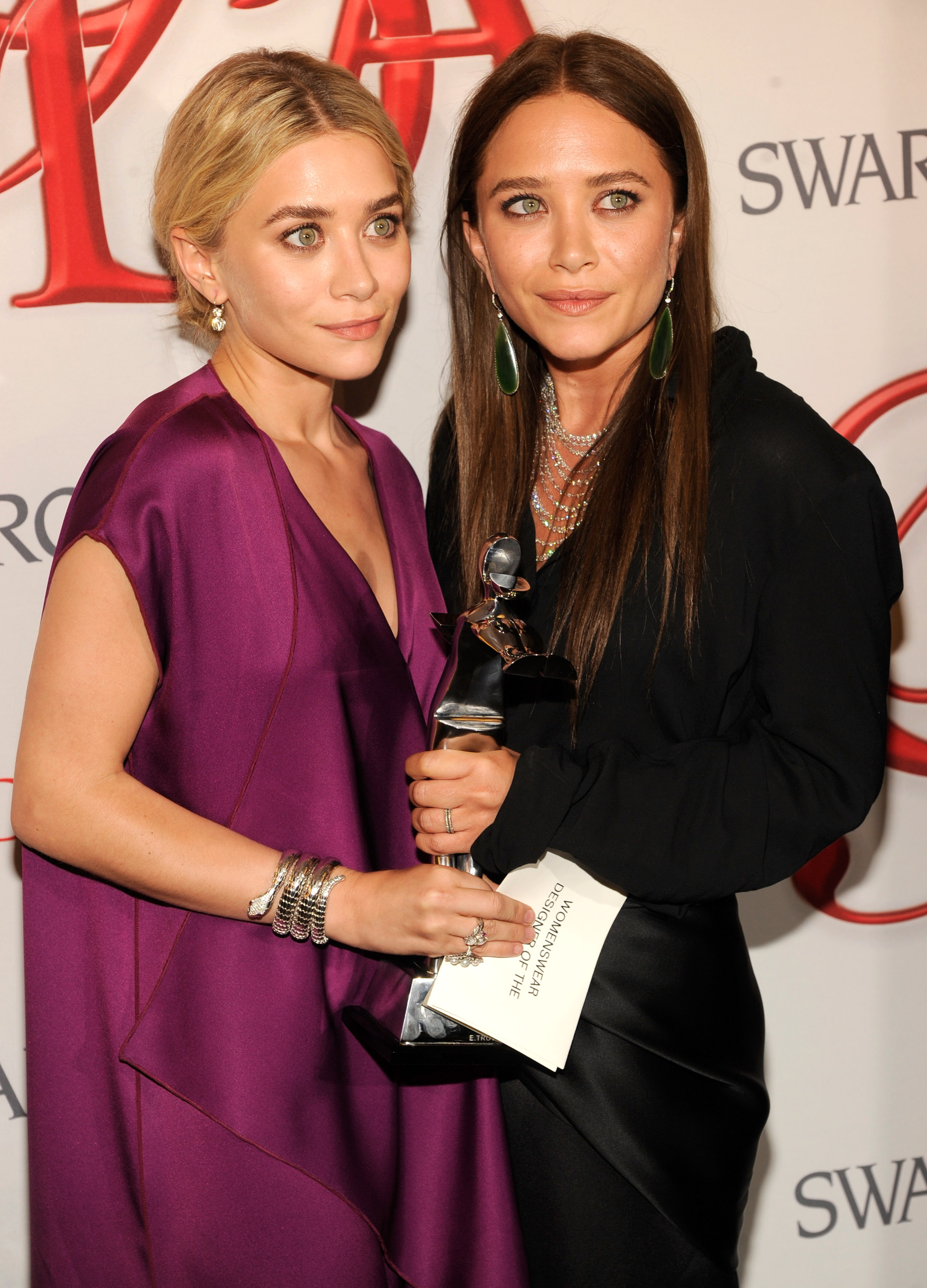 Eine auffallend reife Gesichtsstruktur und elegante Frisuren mit Mittelscheitel prägten das Erscheinungsbild der 26-jährigen Mary-Kate und Ashley Olsen bei den CFDA Fashion Awards am 4. Juni 2012, wo Ashley ein tiefviolettes, drapiertes Abendkleid mit mehreren silbernen Armbändern trug und Mary-Kate sich für eine schwarze Bluse mit langen, glatten dunkelblonden Locken und auffälligen Hängeohrringen entschied.