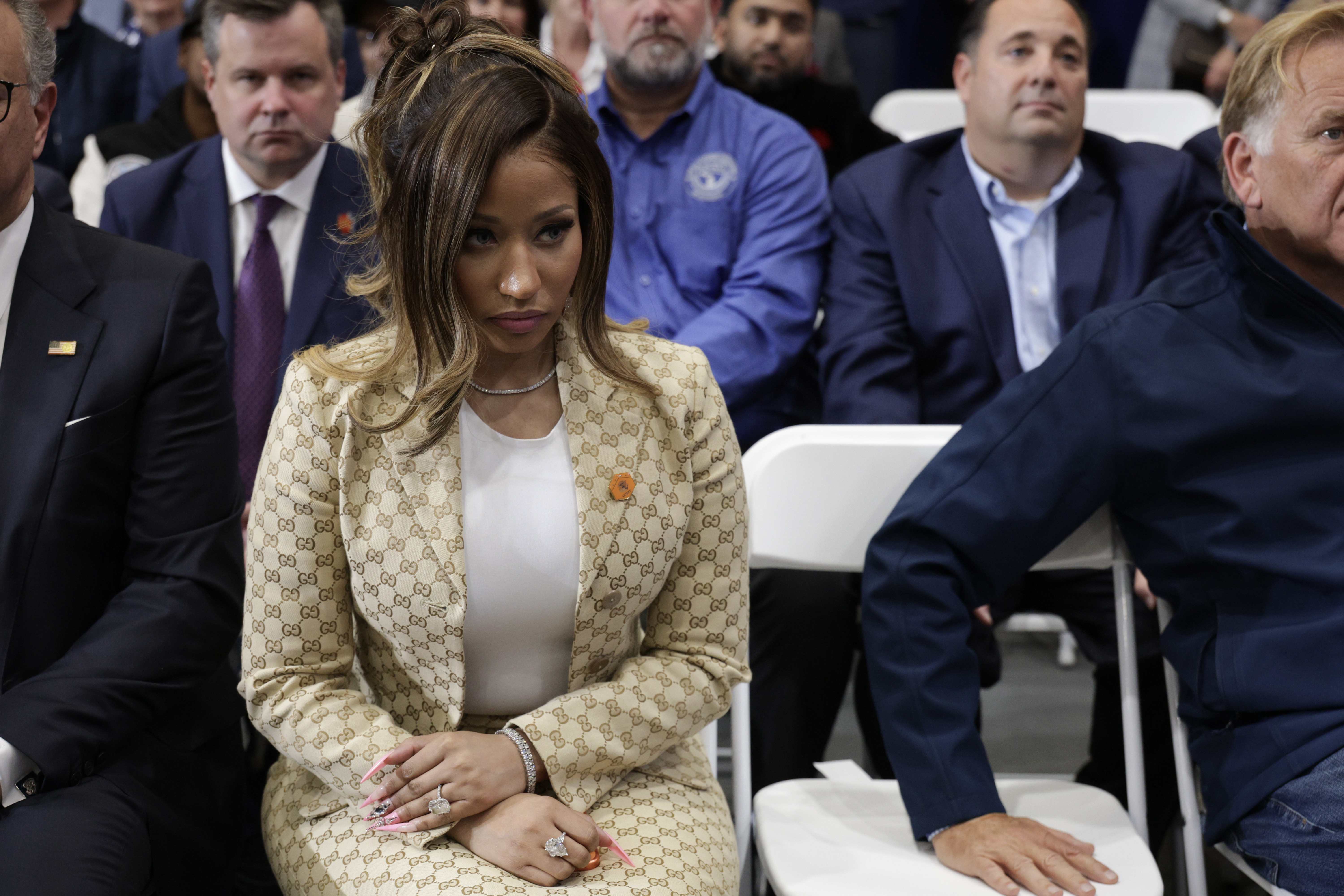 Nicki Minaj sitzt ruhig zwischen den anderen Gästen der Kundgebung, die Hände im Schoß, während sie zur Bühne blickt – ein eher zurückhaltender Moment eines Auftritts, der später für unerwartete Schlagzeilen sorgte. | Quelle: Getty Images