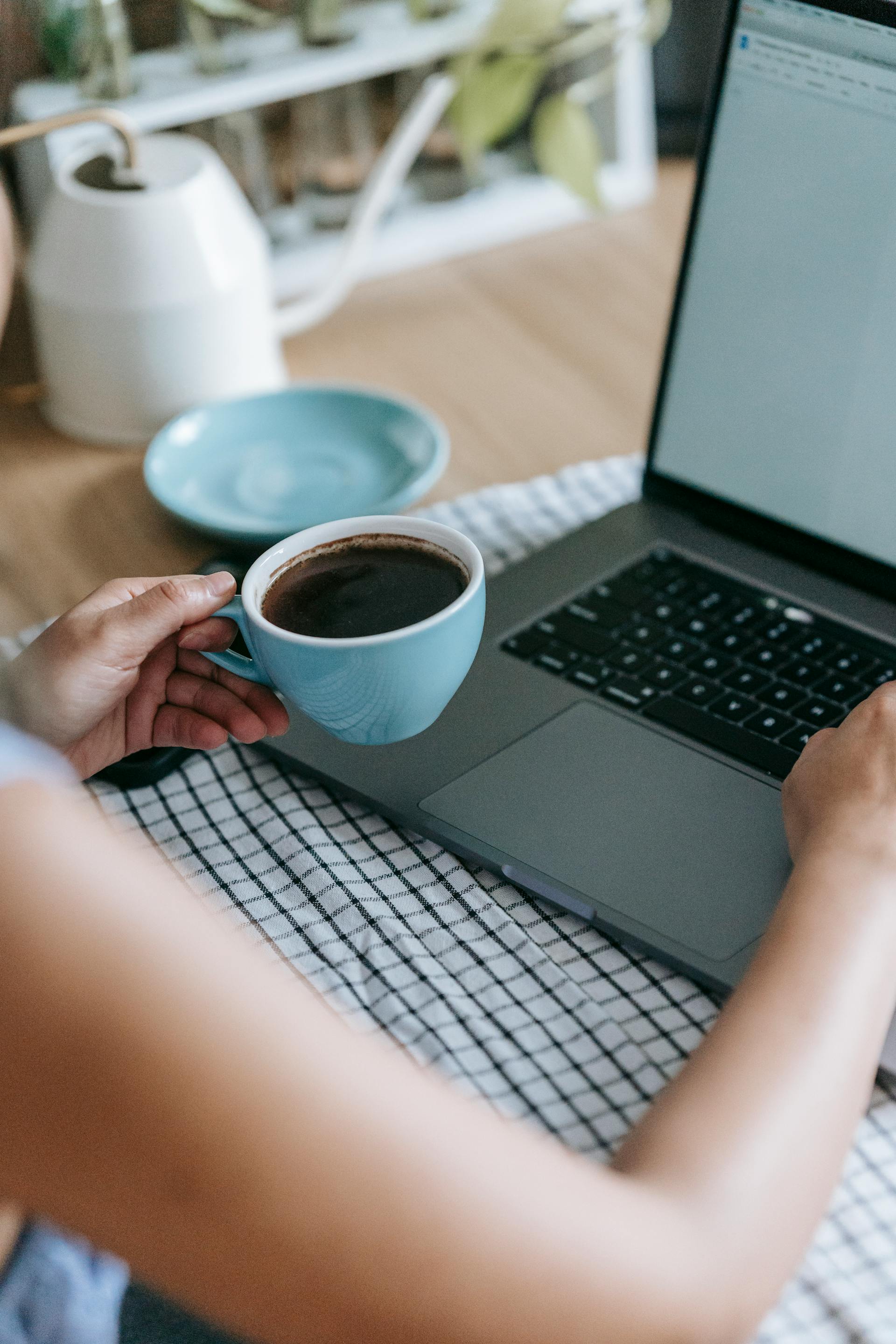 Eine Frau hält eine Tasse Kaffee in der Hand, während sie ihren Laptop benutzt | Quelle: Pexels