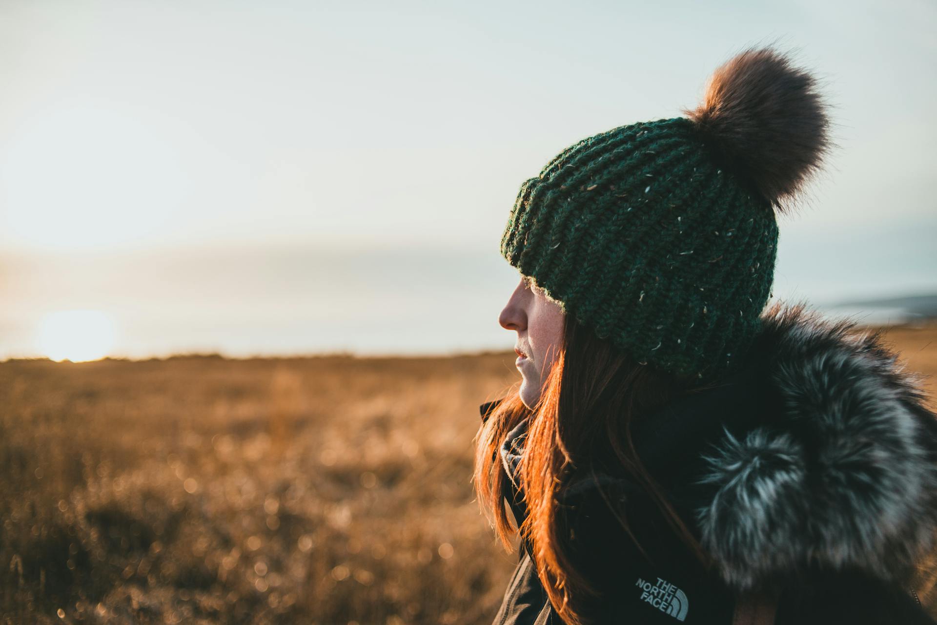 Eine Nahaufnahme einer Frau, die bei Sonnenuntergang die Natur auf einer Wiese am Meer bewundert | Quelle: Pexels