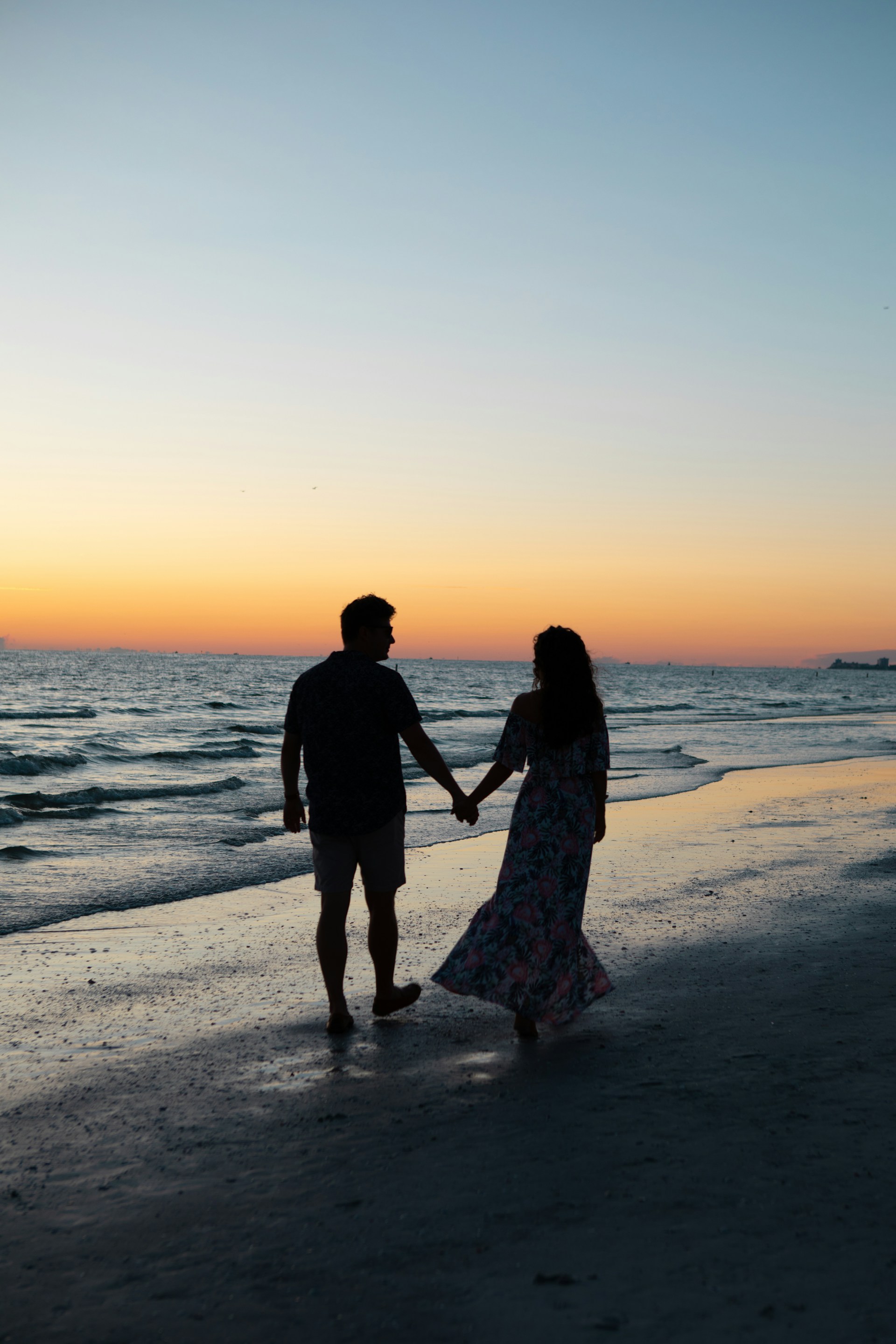 Ein junges romantisches Paar, das an einem schönen Abend am Strand spazieren geht | Quelle: Unsplash