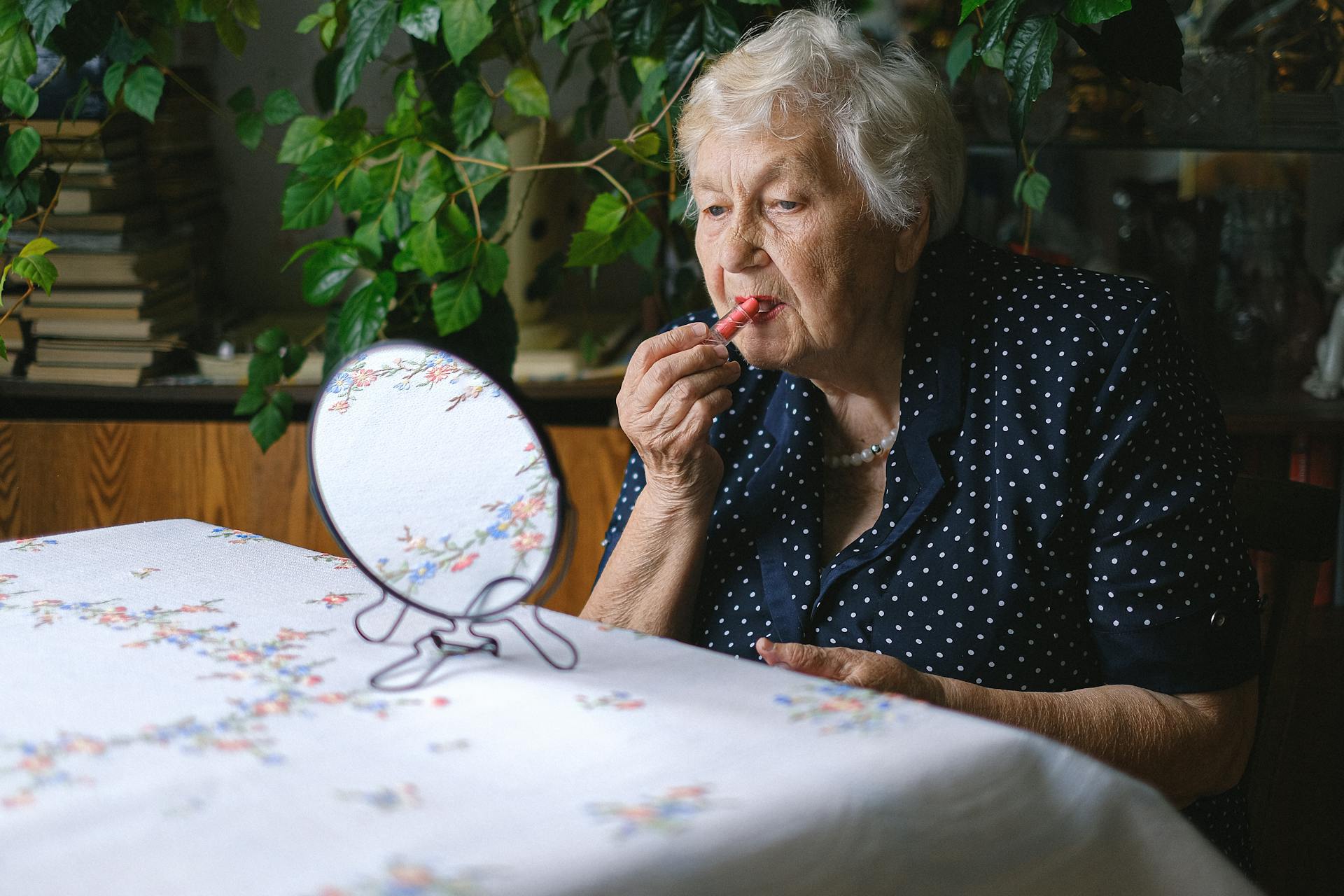 Eine alte Frau trägt Lippenstift auf | Quelle: Pexels