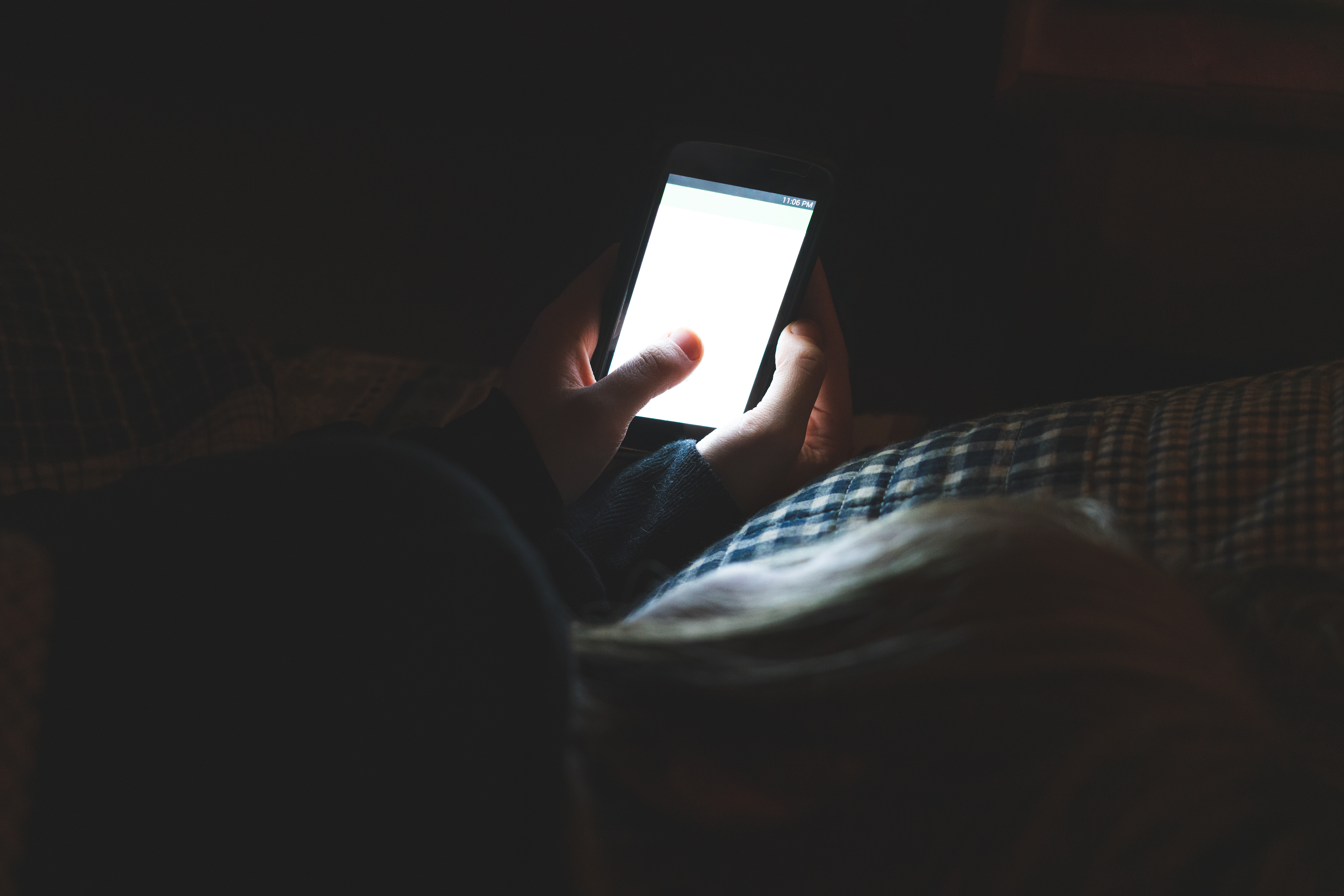 Eine Person hält ein Smartphone in einem dunklen Raum | Quelle: Shutterstock
