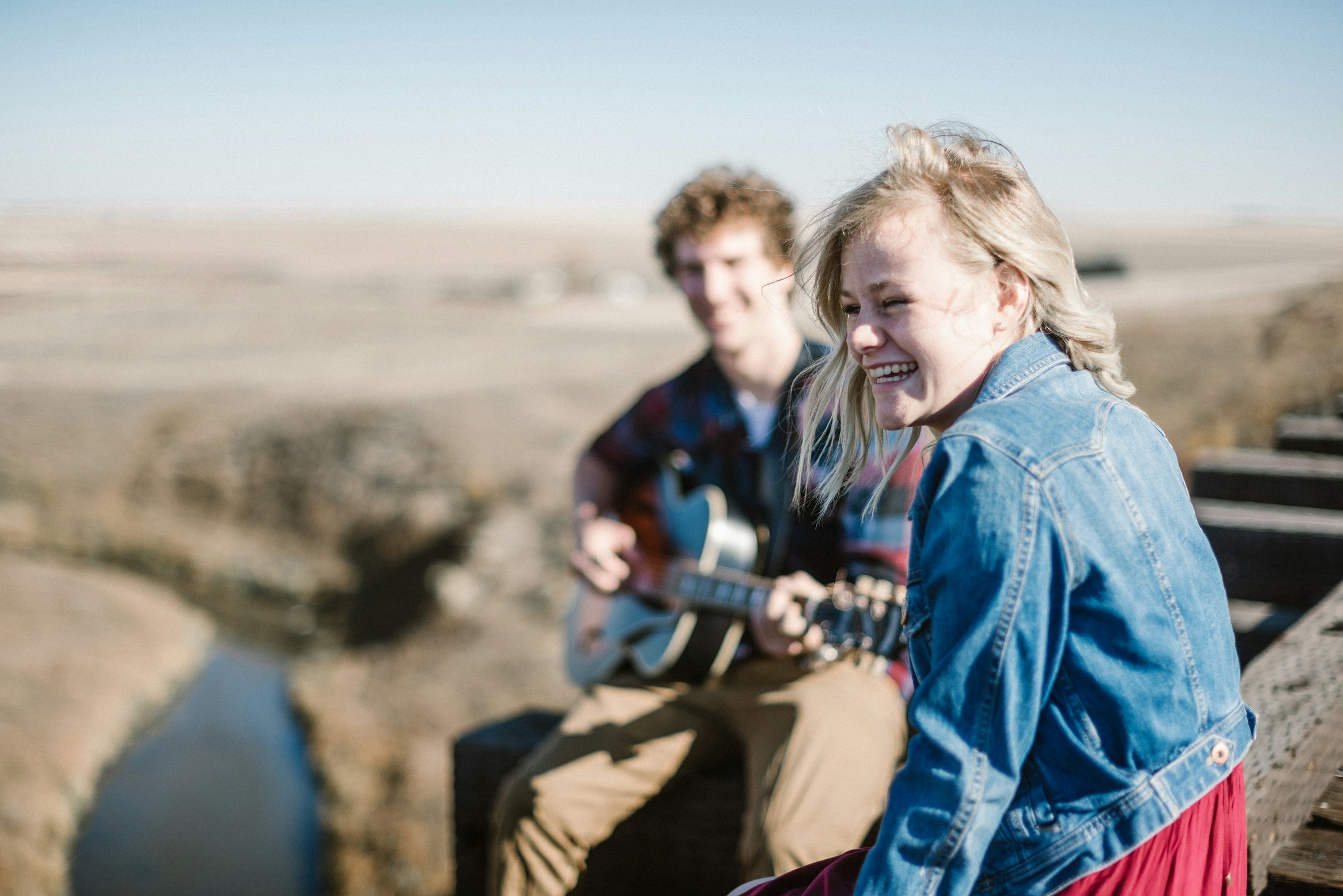 Eine lächelnde Frau, die neben einem Gitarre spielenden Mann sitzt | Quelle: Unsplash