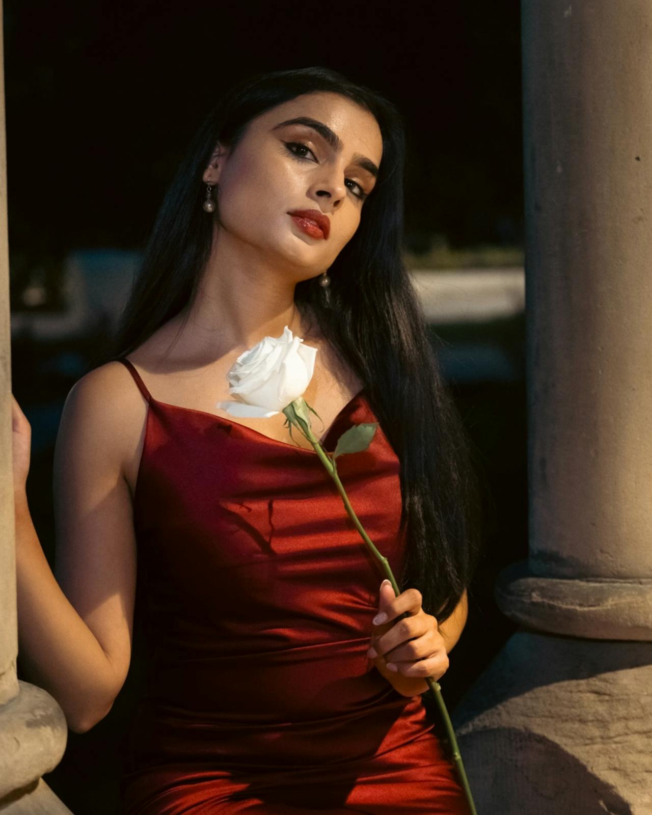 Eine Frau in einem roten Kleid hält eine Rose | Quelle: Pexels