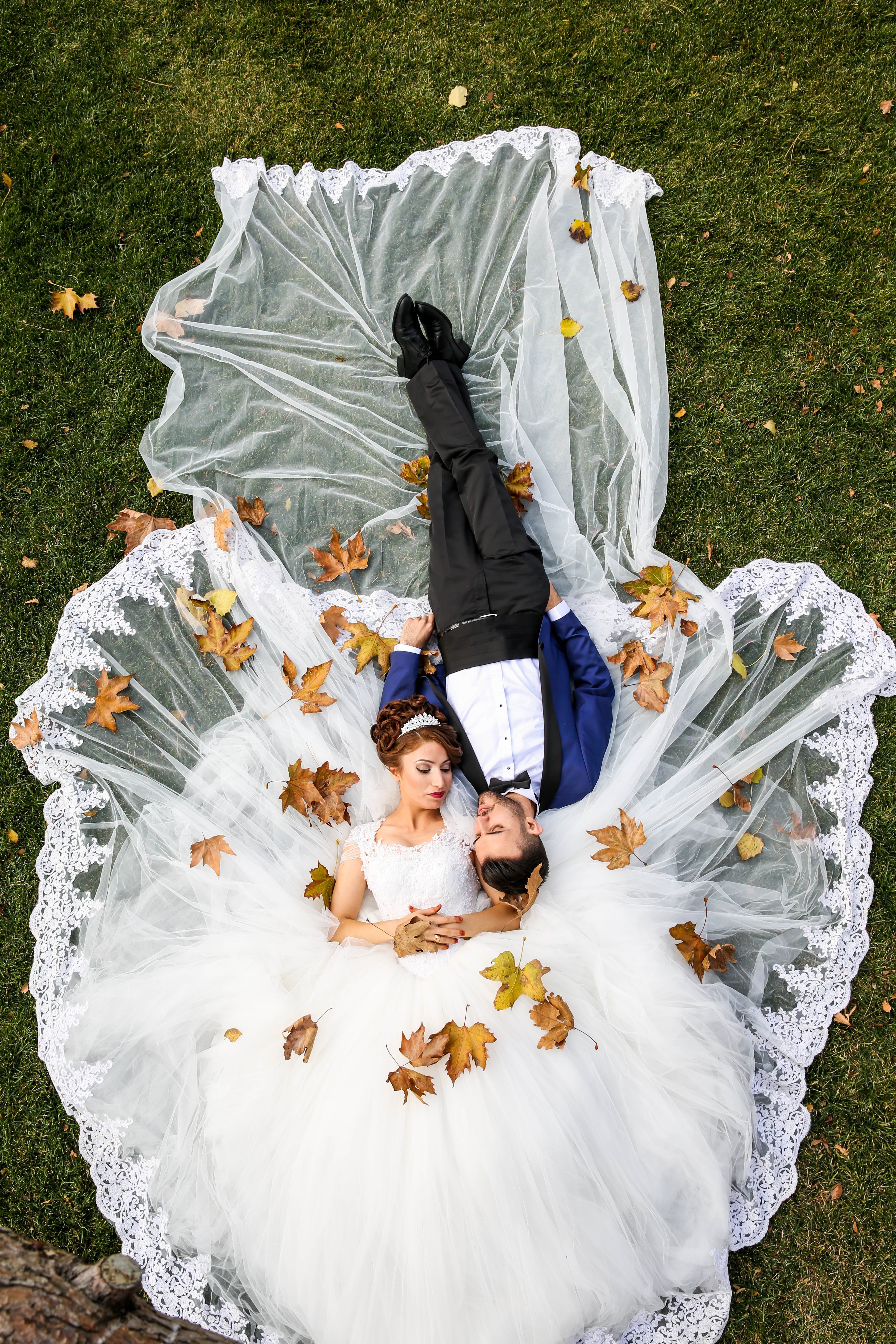 Ein frisch vermähltes Paar, das in seiner Hochzeitskleidung auf dem Rasen liegt | Quelle: Pexels