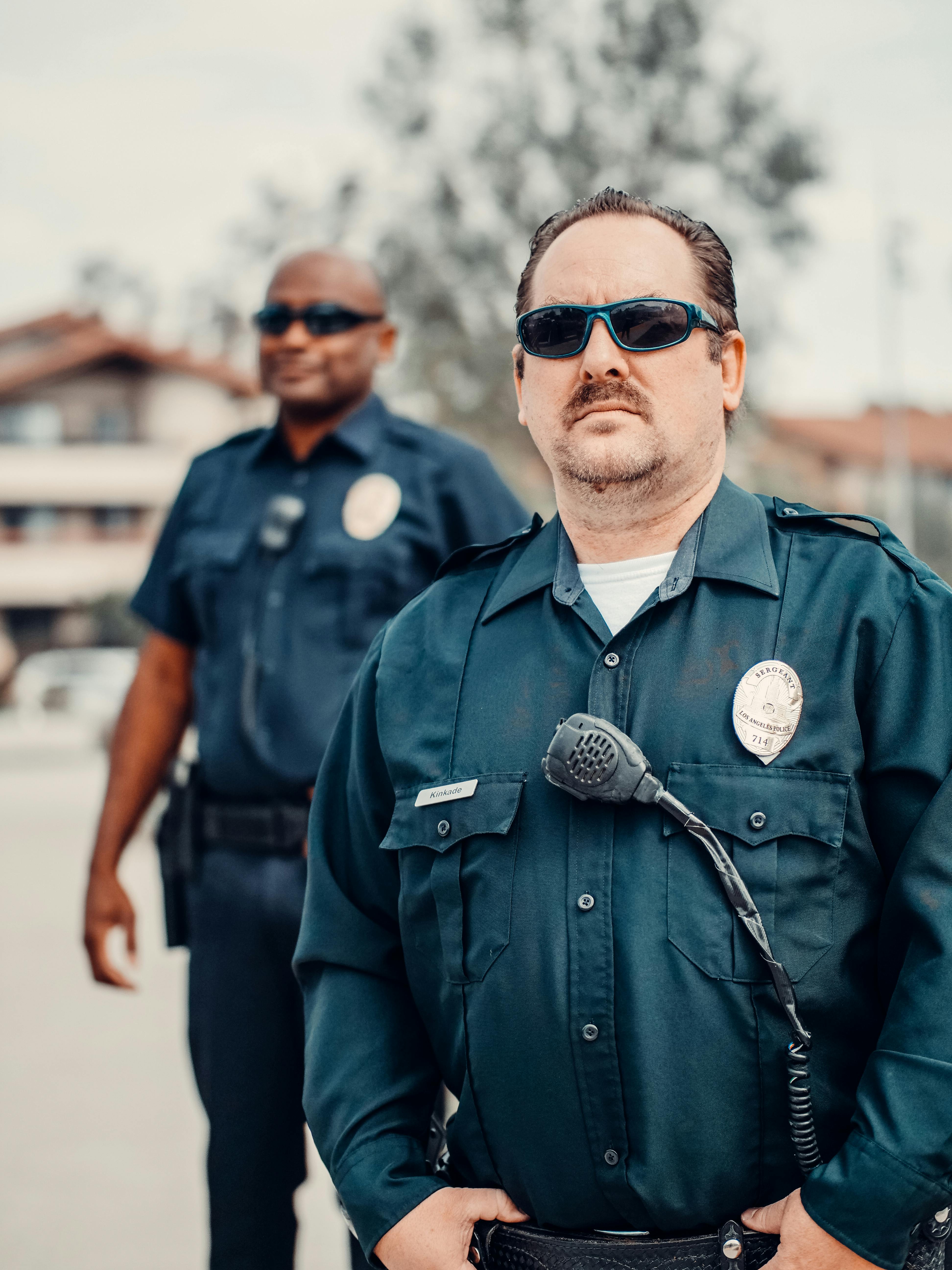 Ein düster aussehender Polizist steht hinter einem Kollegen | Quelle: Pexels
