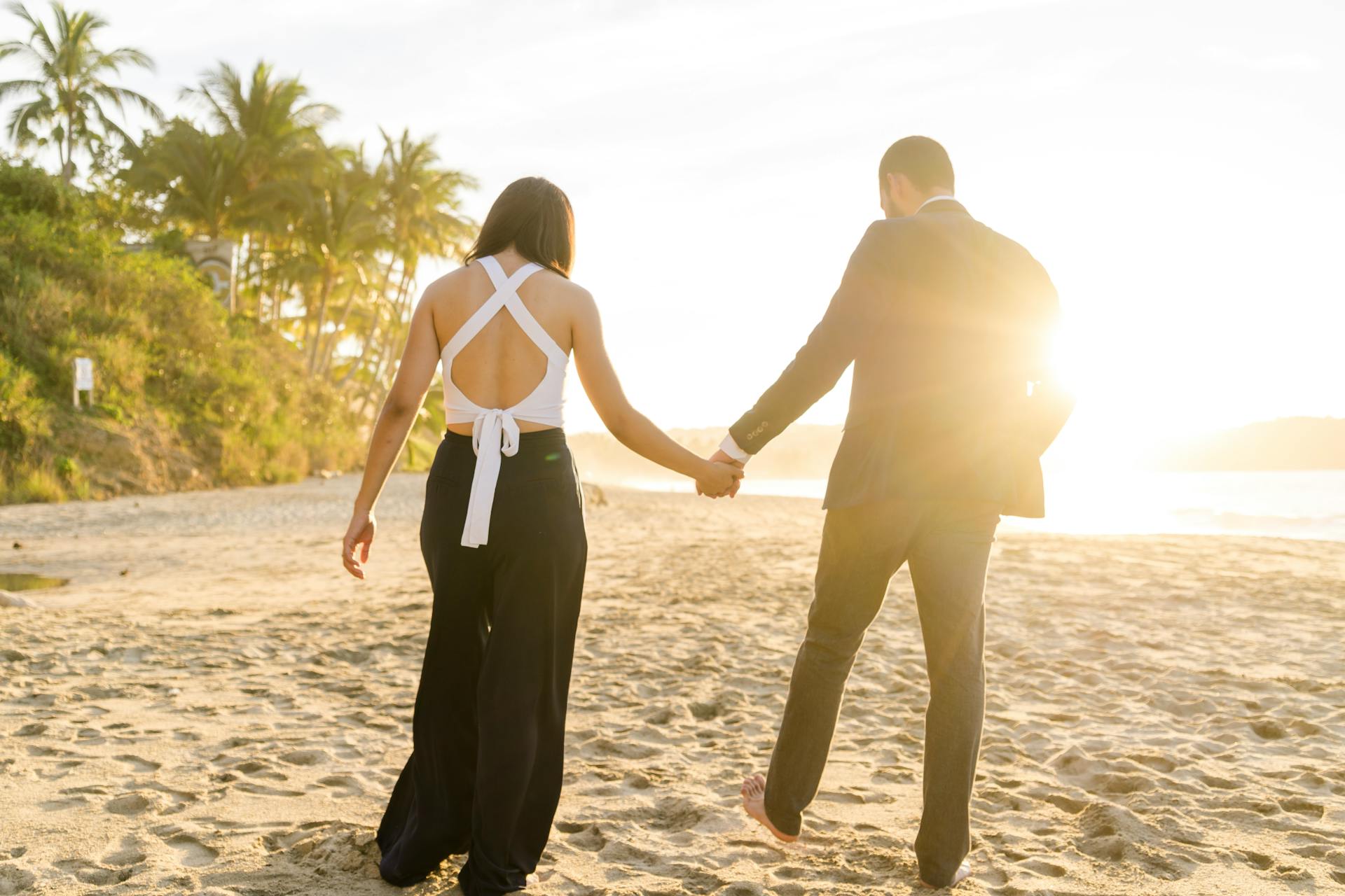 Rückansicht eines Paares, das am Strand spazieren geht | Quelle: Pexels