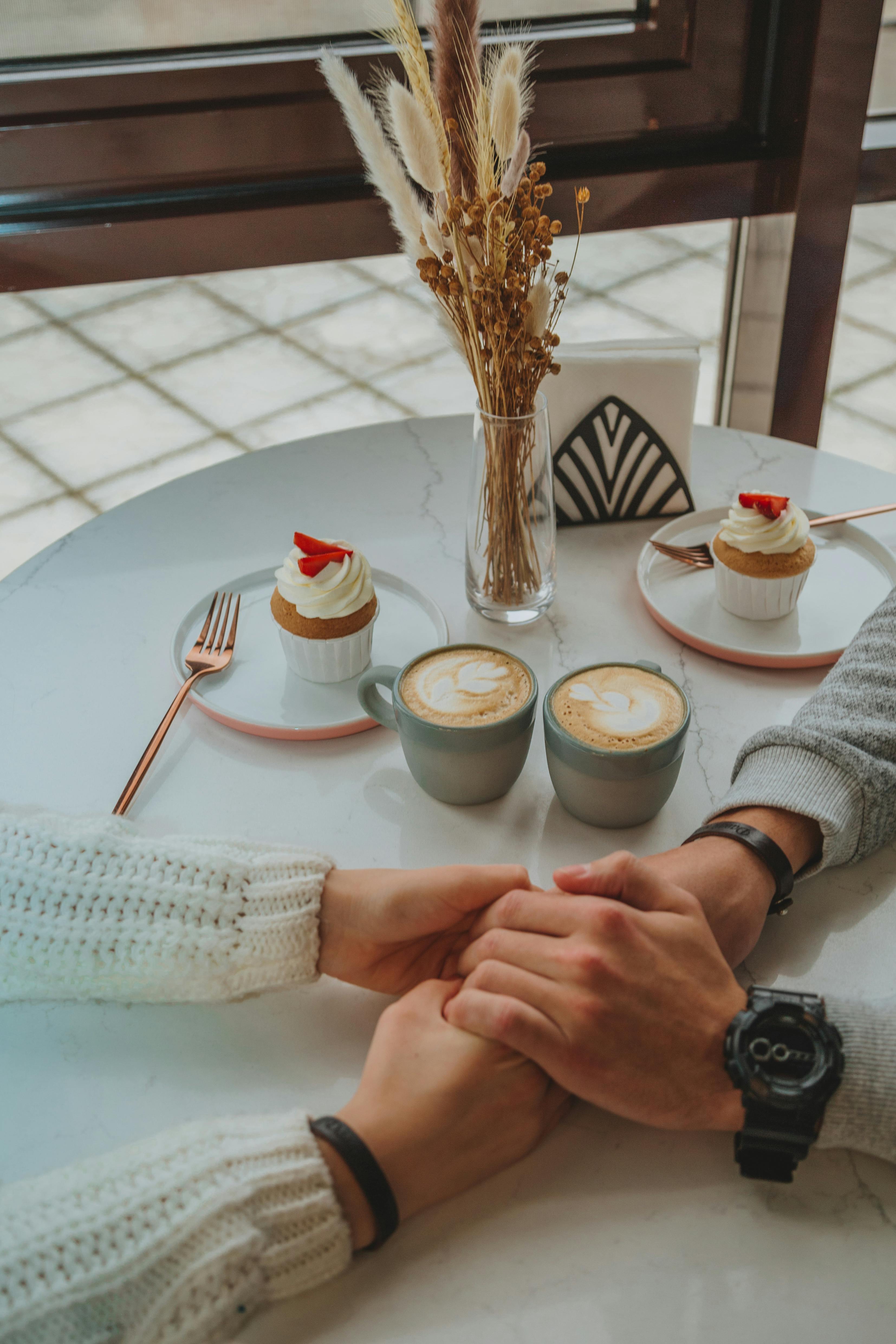 Ein Paar hält sich an den Händen, während es Nachtisch und Kaffee genießt | Quelle: Pexels