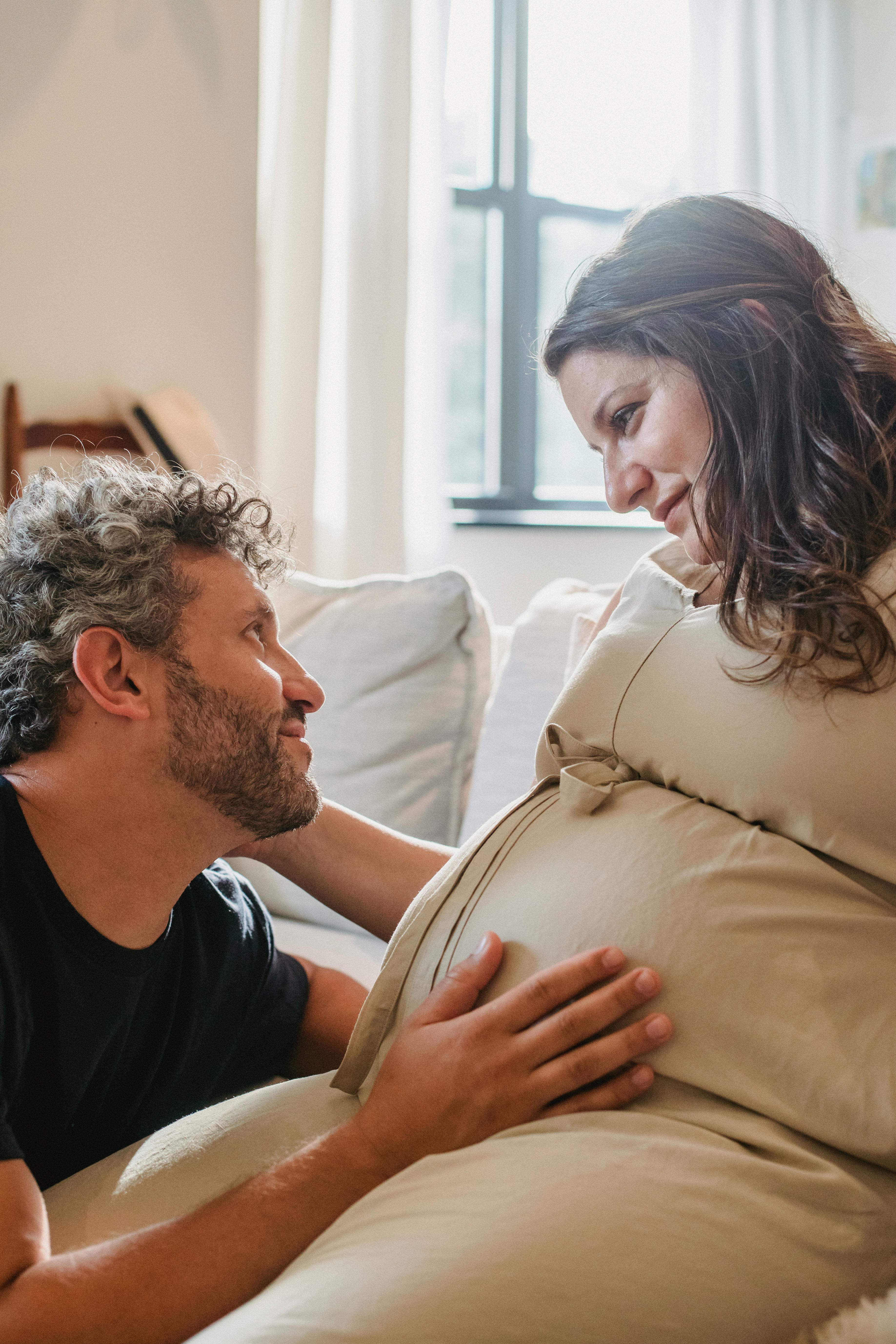Ein Mann berührt den Bauch seiner schwangeren Frau, während sie sich gegenseitig anstarren | Quelle: Pexels