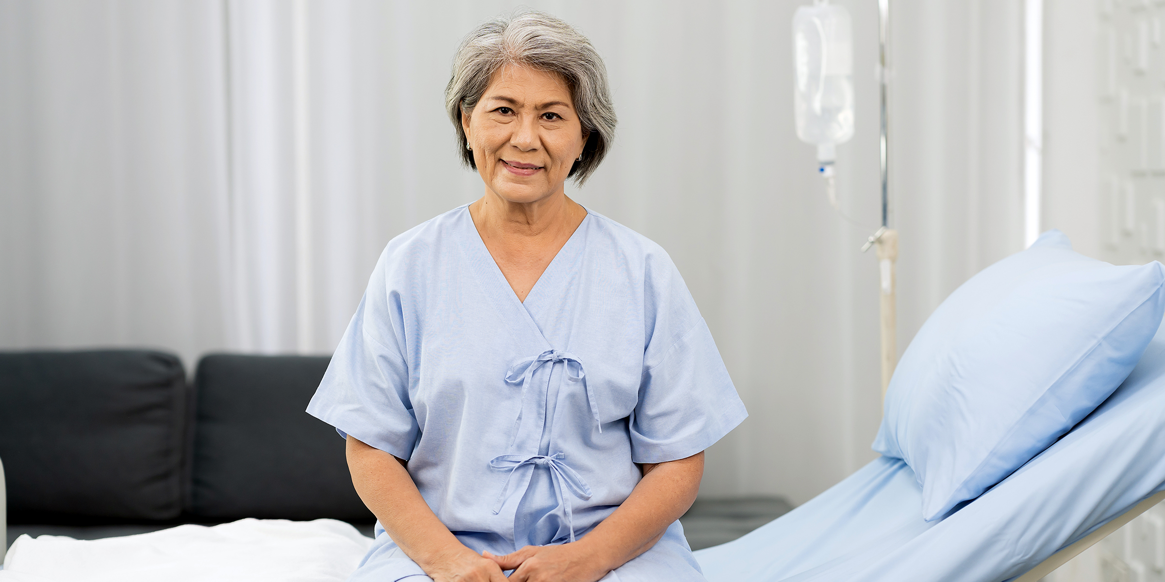 Eine alte Frau, die auf einem Krankenhausbett sitzt | Quelle: Shutterstock