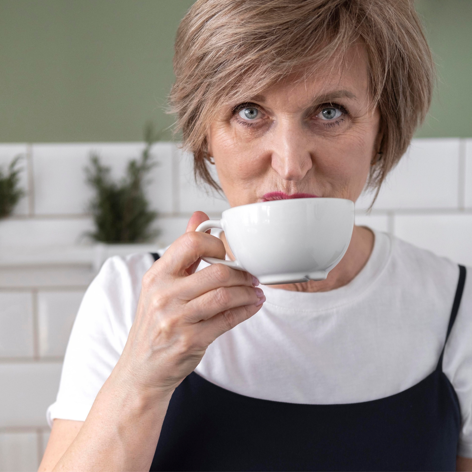 Eine lächelnde ältere Frau, die eine Keramiktasse hält | Quelle: Freepik