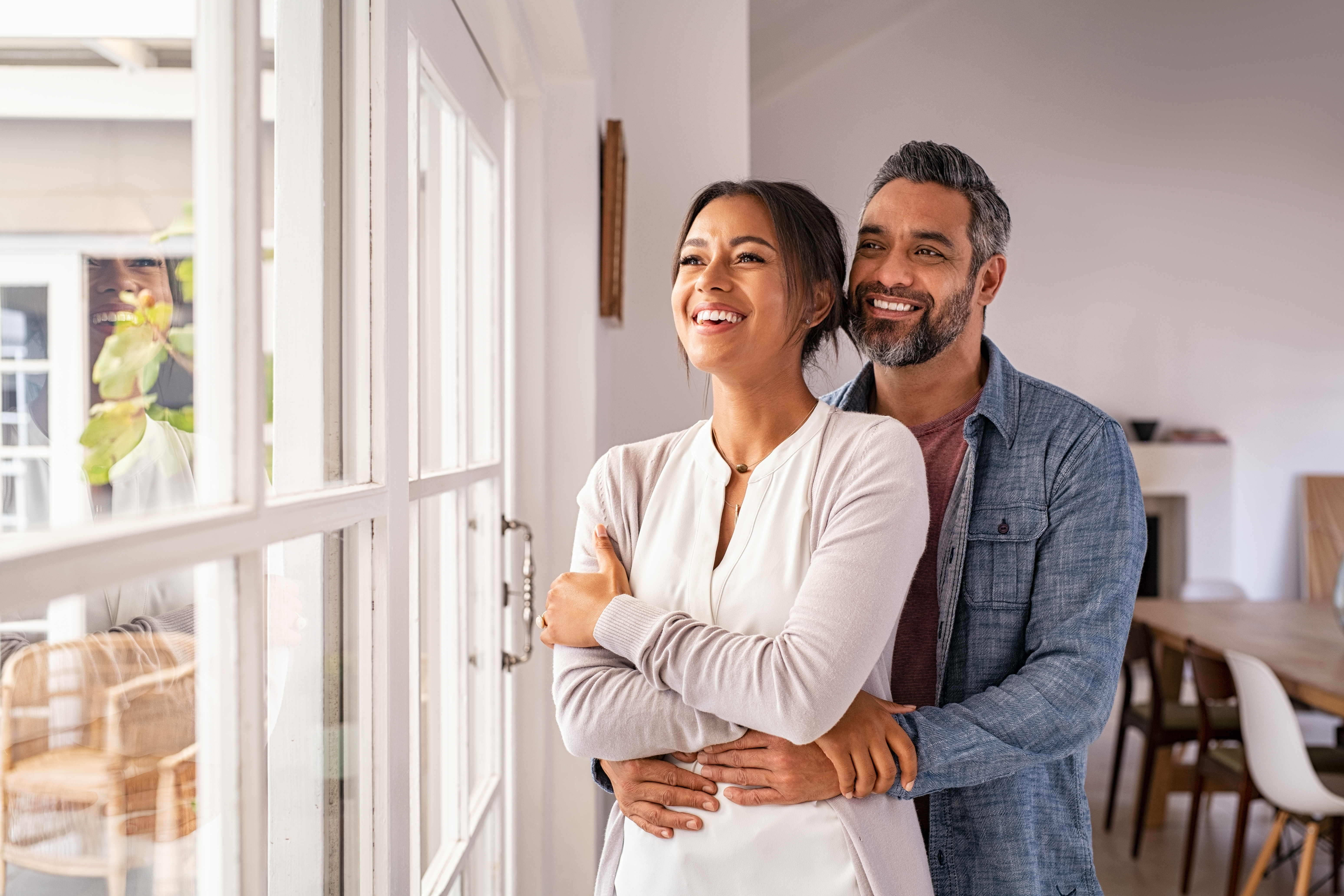 Ein Mann und eine Frau lächeln, während sie aus einem Fenster schauen | Quelle: Shutterstock