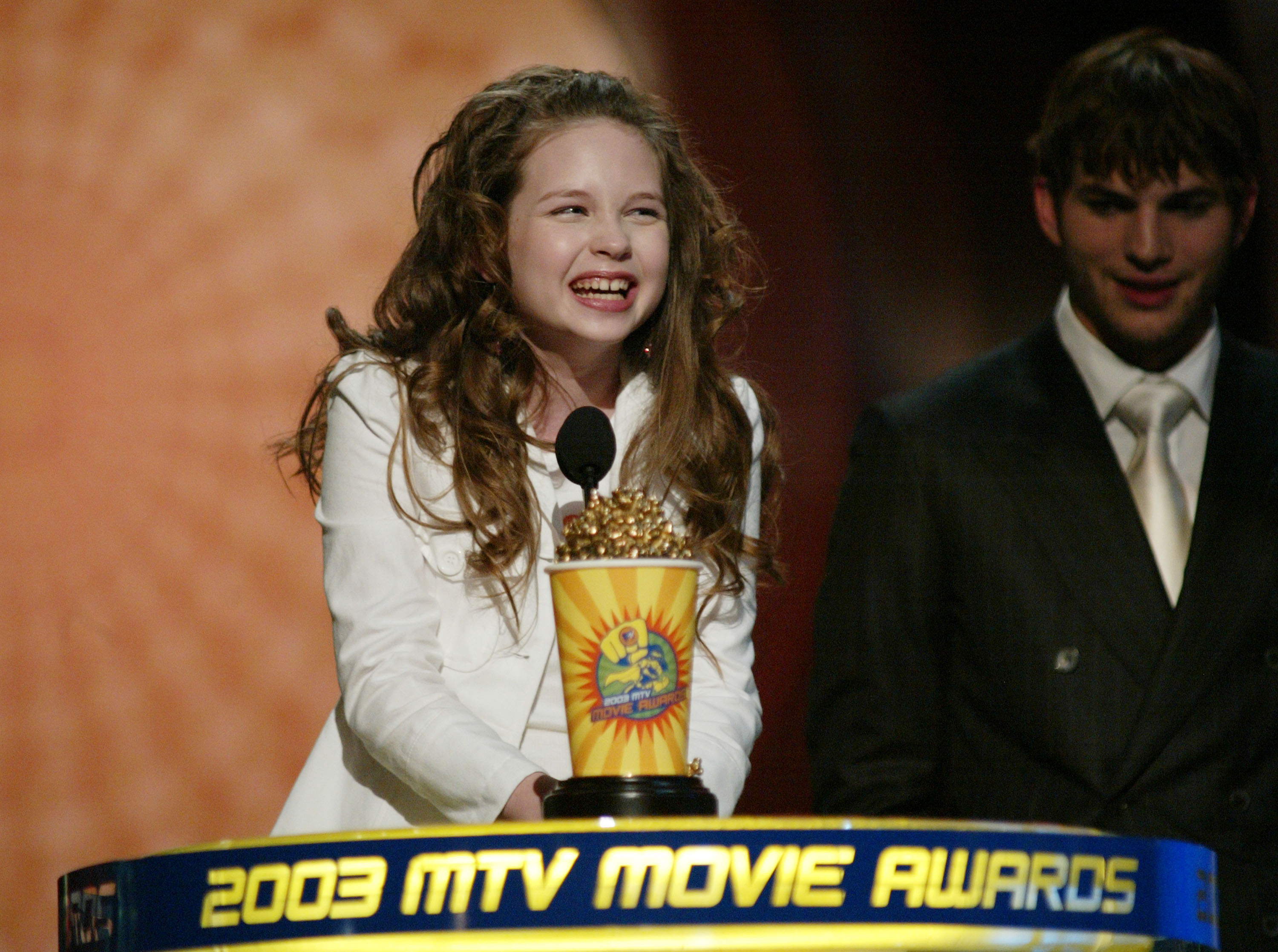 Daveigh Chase nimmt bei den MTV Movie Awards 2003 gemeinsam mit Ashton Kutcher auf der Bühne einen Preis entgegen, nachdem sie für ihre Rolle in „The Ring“ als beste Bösewichtin ausgezeichnet wurde. | Quelle: Getty Images