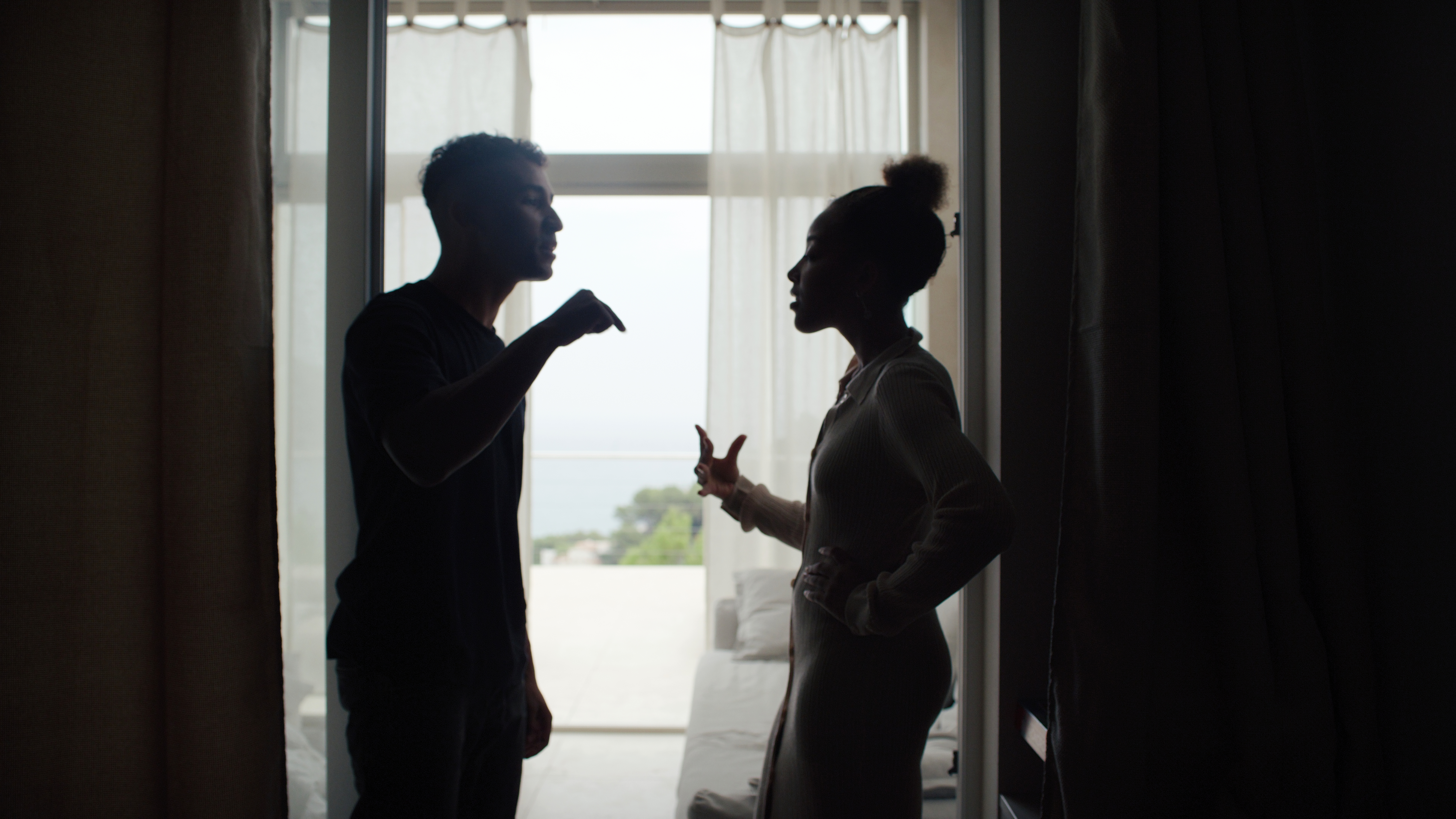 Ein unglückliches, afrikanischstämmiges Paar streitet und gestikuliert im Wohnzimmer. Beziehungskrise | Quelle: Getty Images