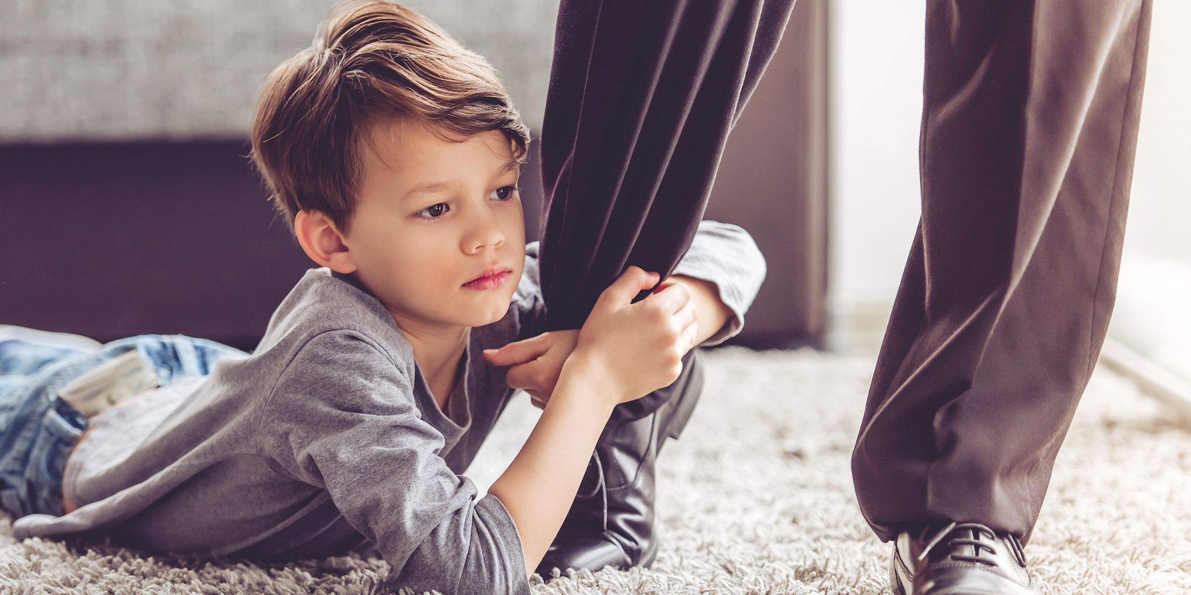 Ein Kind, das sich am Bein eines Erwachsenen festhält | Quelle: Shutterstock