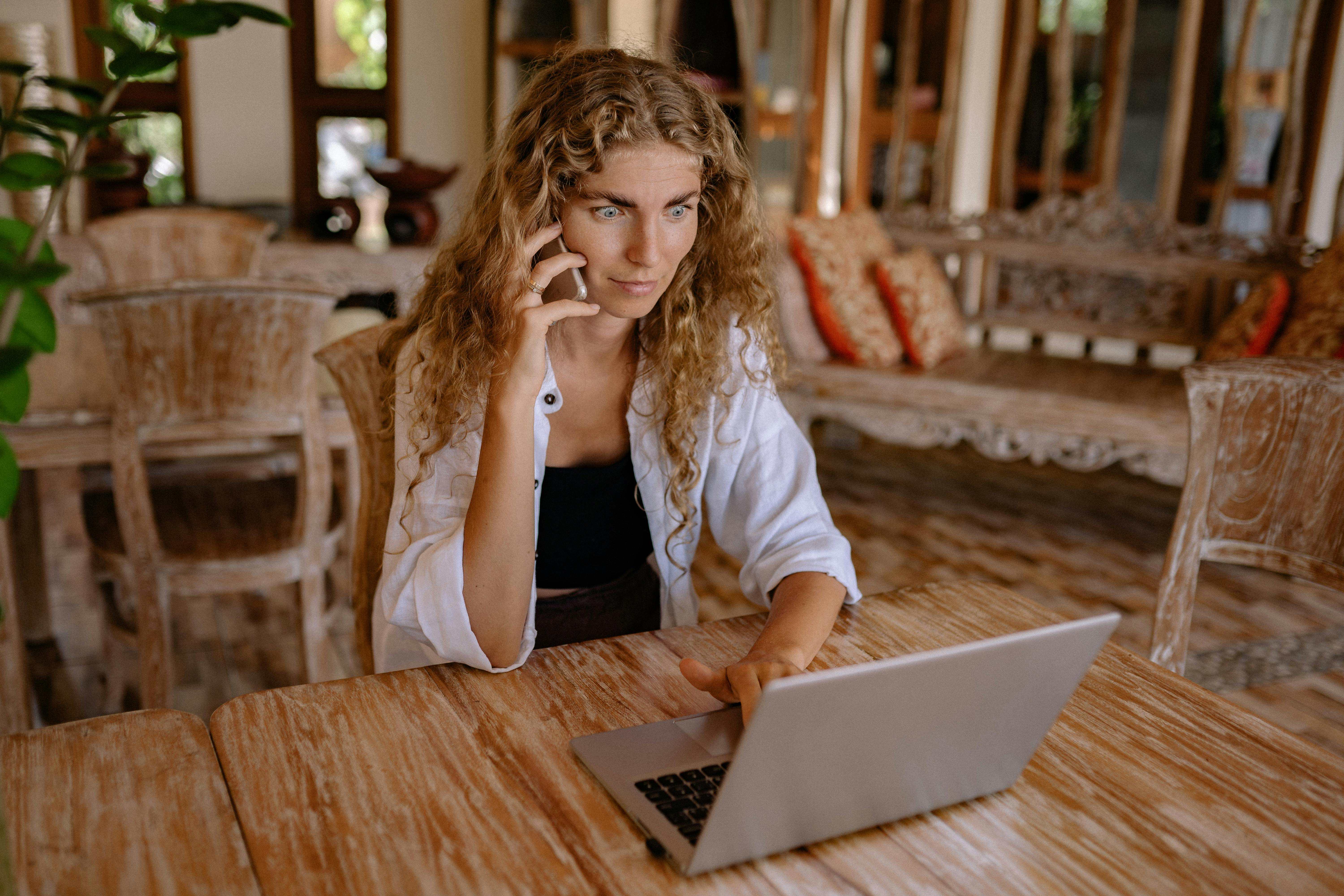 Eine Frau telefoniert, während sie einen Laptop benutzt | Quelle: Pexels