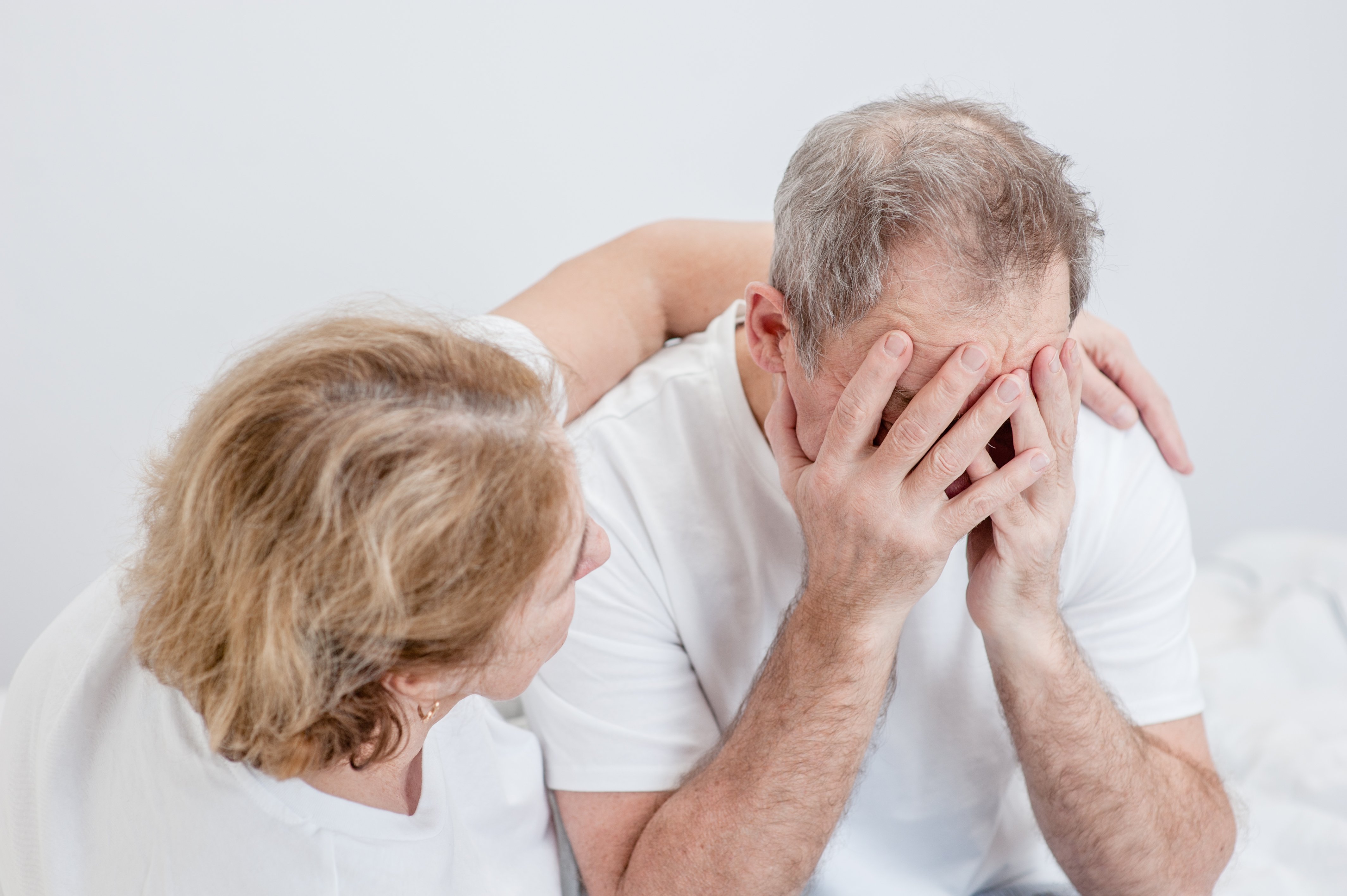 Eine Frau tröstet einen traurigen älteren Mann | Quelle: Shutterstock