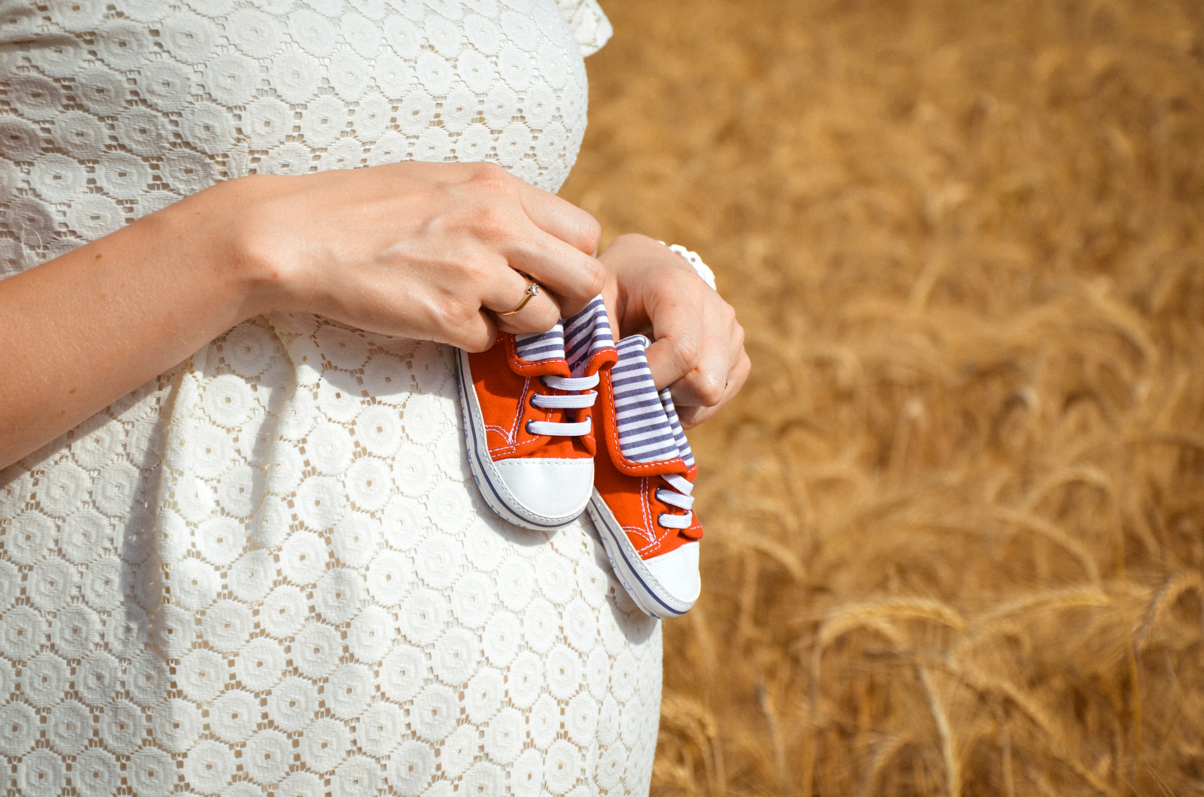 Eine schwangere Frau mit winzigen Babyschuhen | Quelle: Unsplash