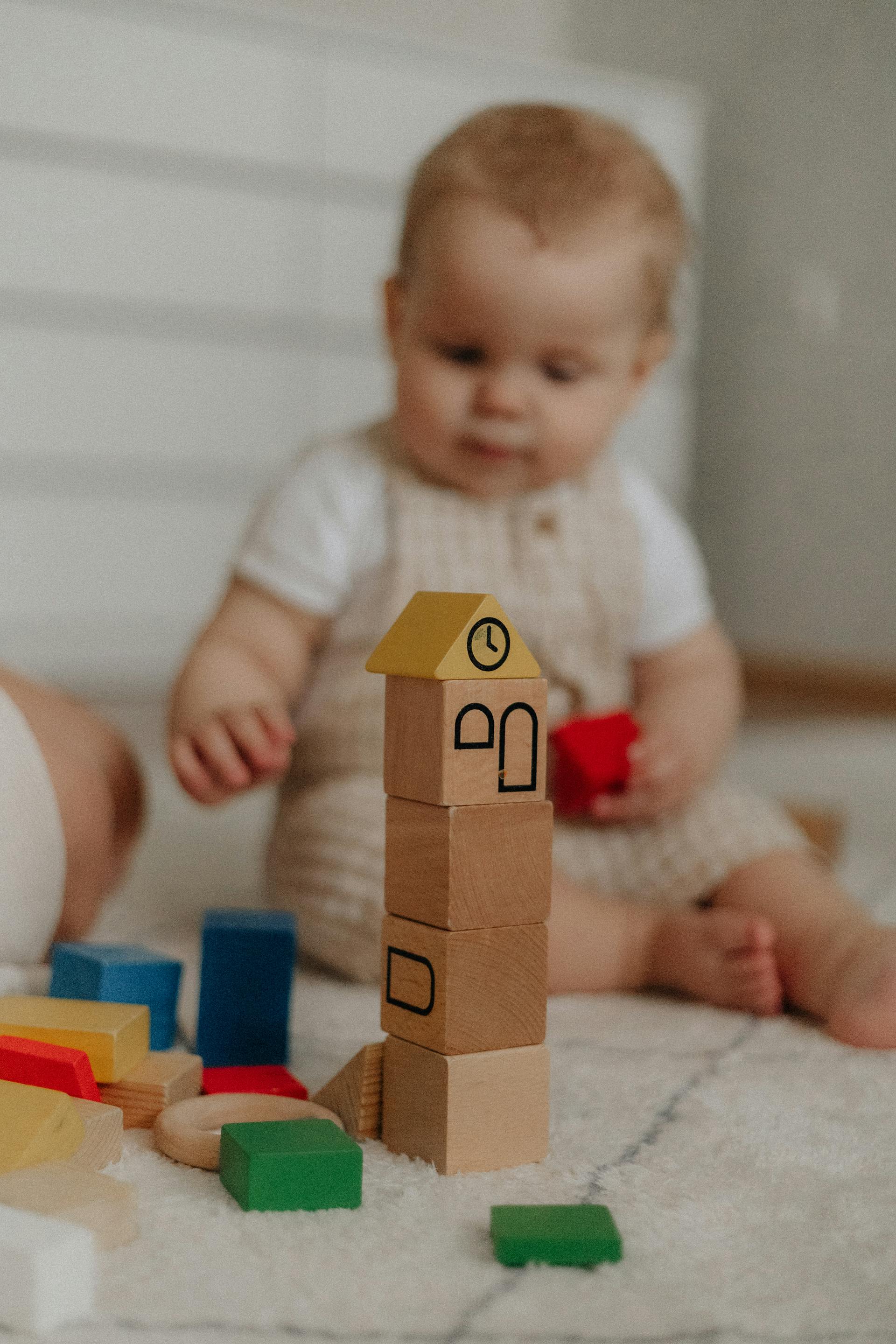 Ein Baby sitzt auf dem Teppich und spielt mit Bauklötzen | Quelle: Pexels